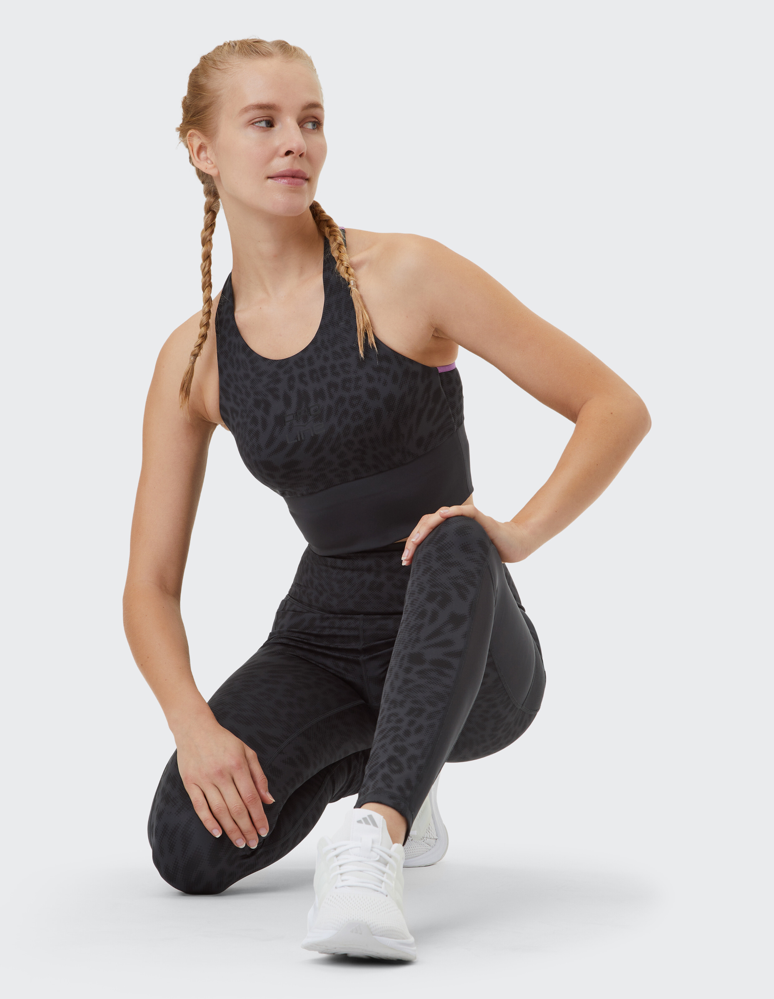 Frau in schwarzem Activewear-Set mit Leopardenmuster, perfekt für Workouts oder Freizeitausflüge.