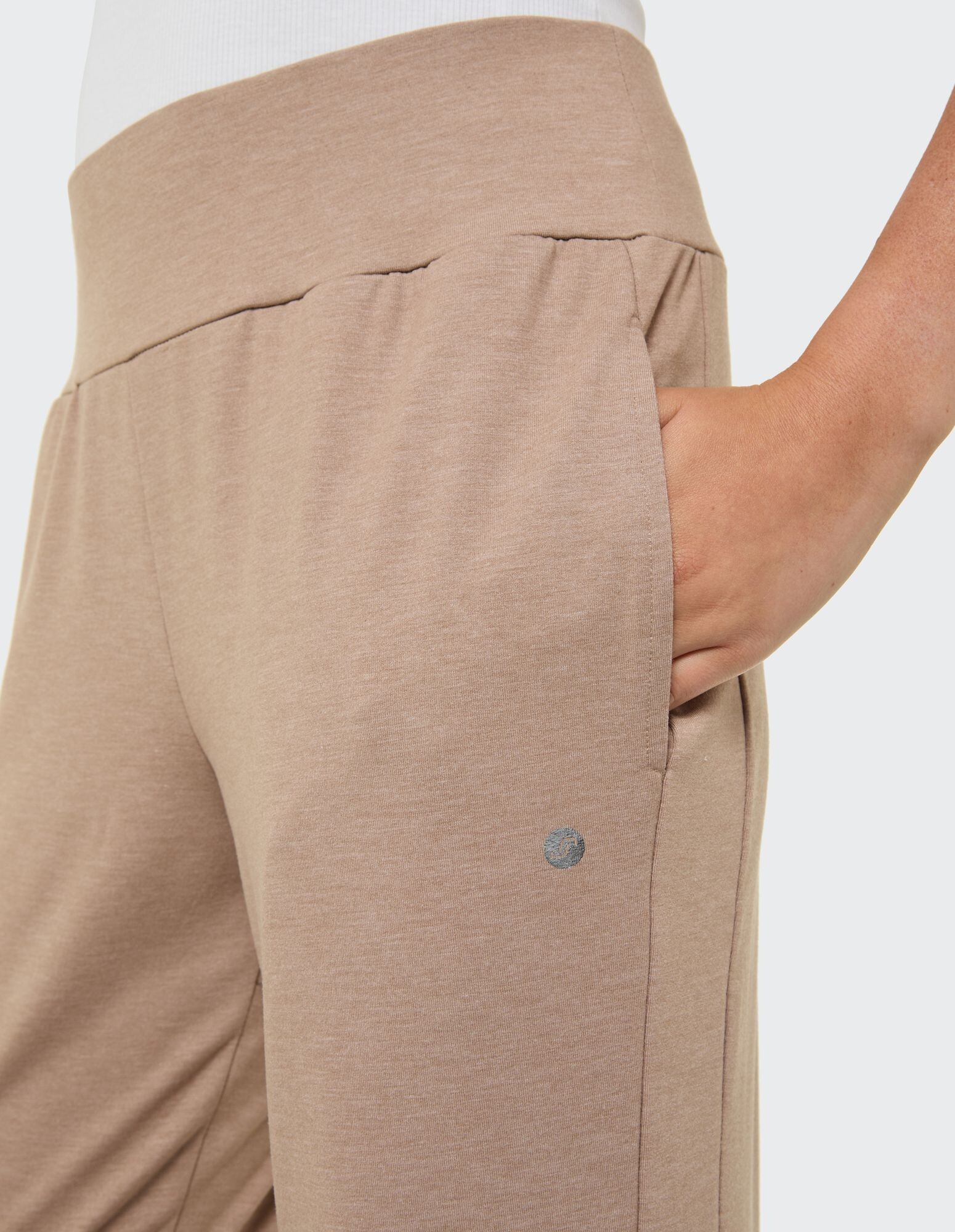 Nahaufnahme einer beigen Freizeithose mit breitem Bund und Seitentasche.