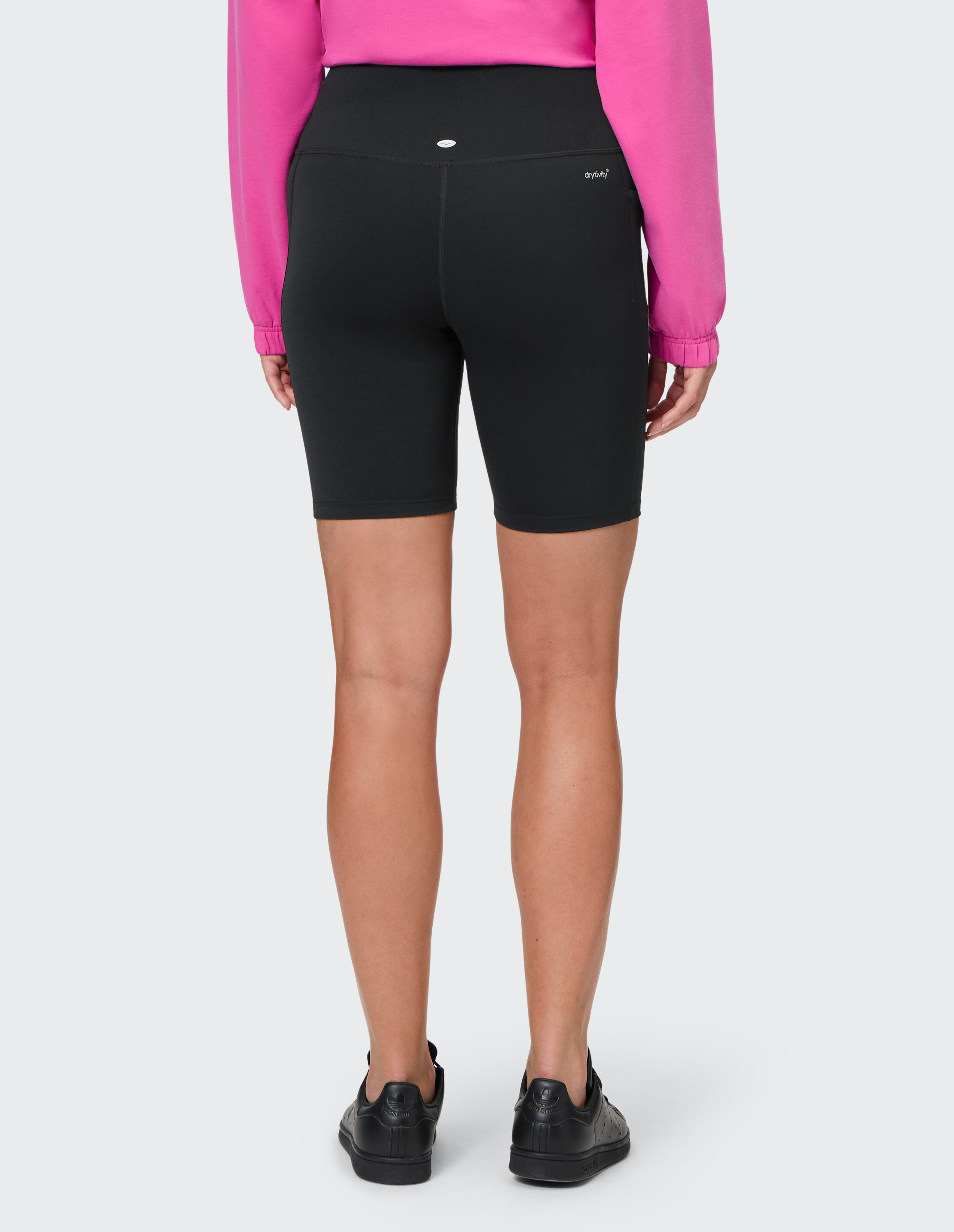 Rückansicht einer schwarzen Biker-Shorts mit hoher Taille, gepaart mit einem leuchtend rosa Freizeit-Top.