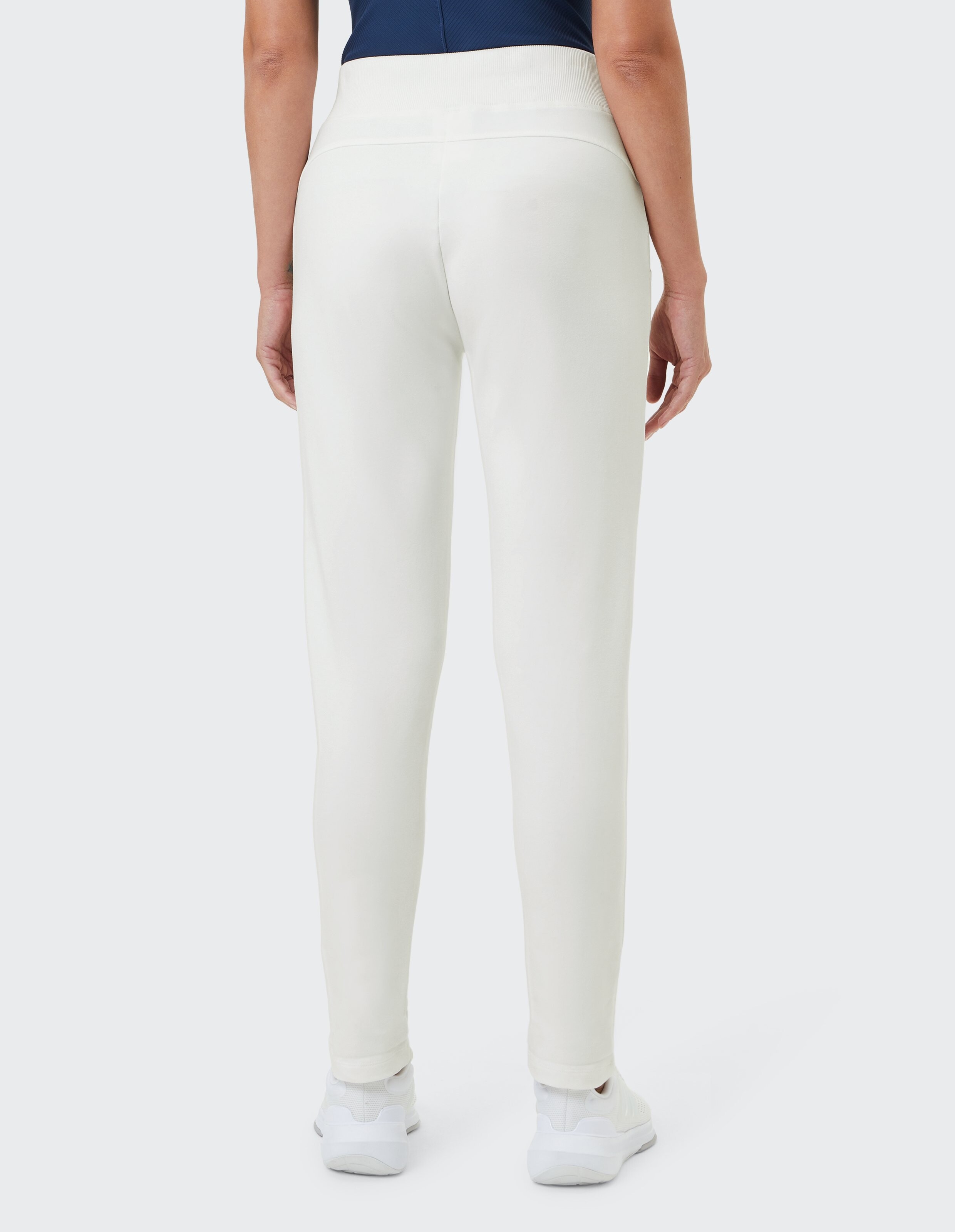 Rückansicht einer Frau, die eine gemütliche, lässige Lounge-Hose in Cremeweiß mit hohem Bund trägt.