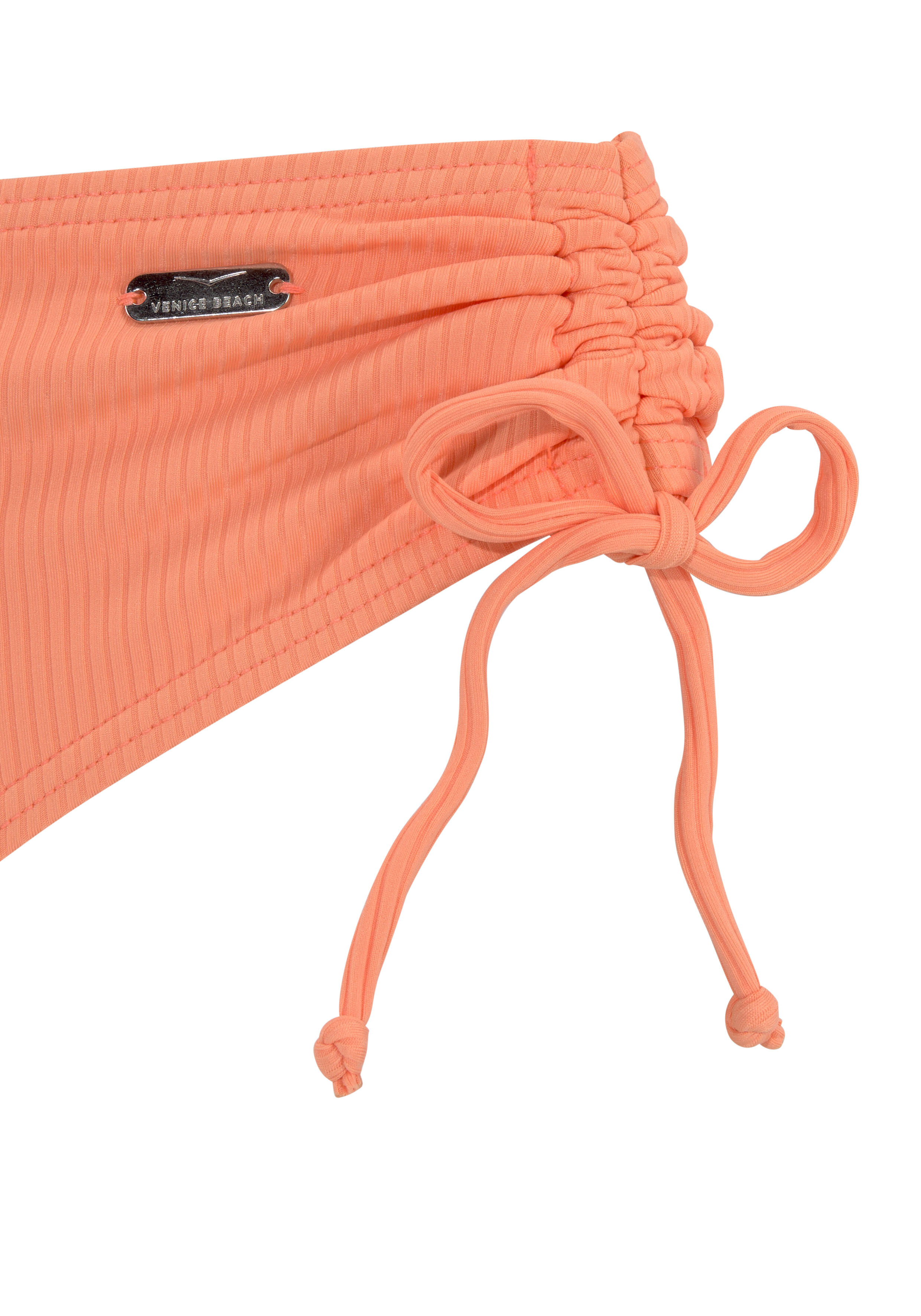 Nahaufnahme einer korallenroten, gerippten Bikinihose mit verstellbarem Bindedetail.