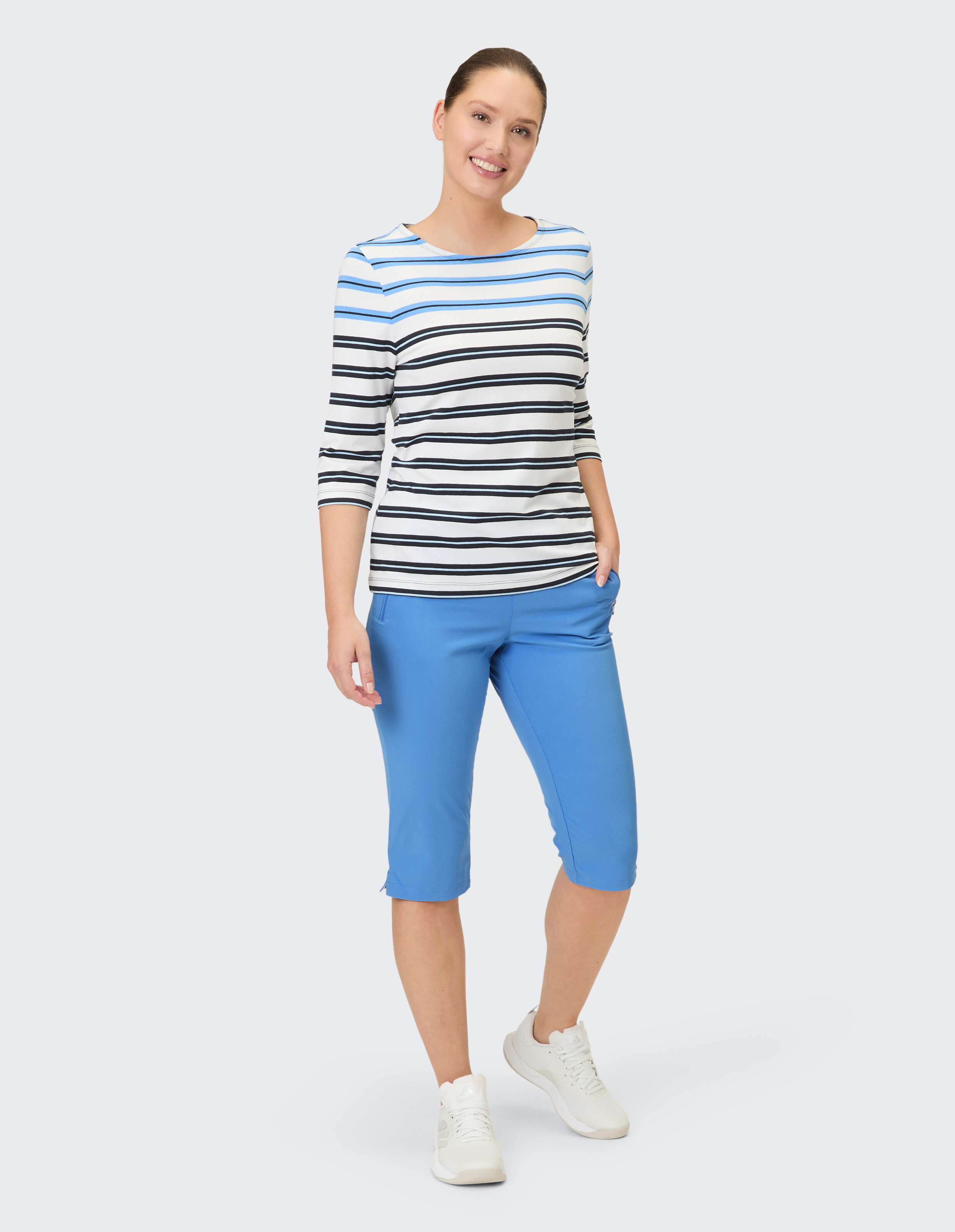 Frau in gestreiftem Oberteil und blauer Caprihose, perfekt für Freizeitausflüge.