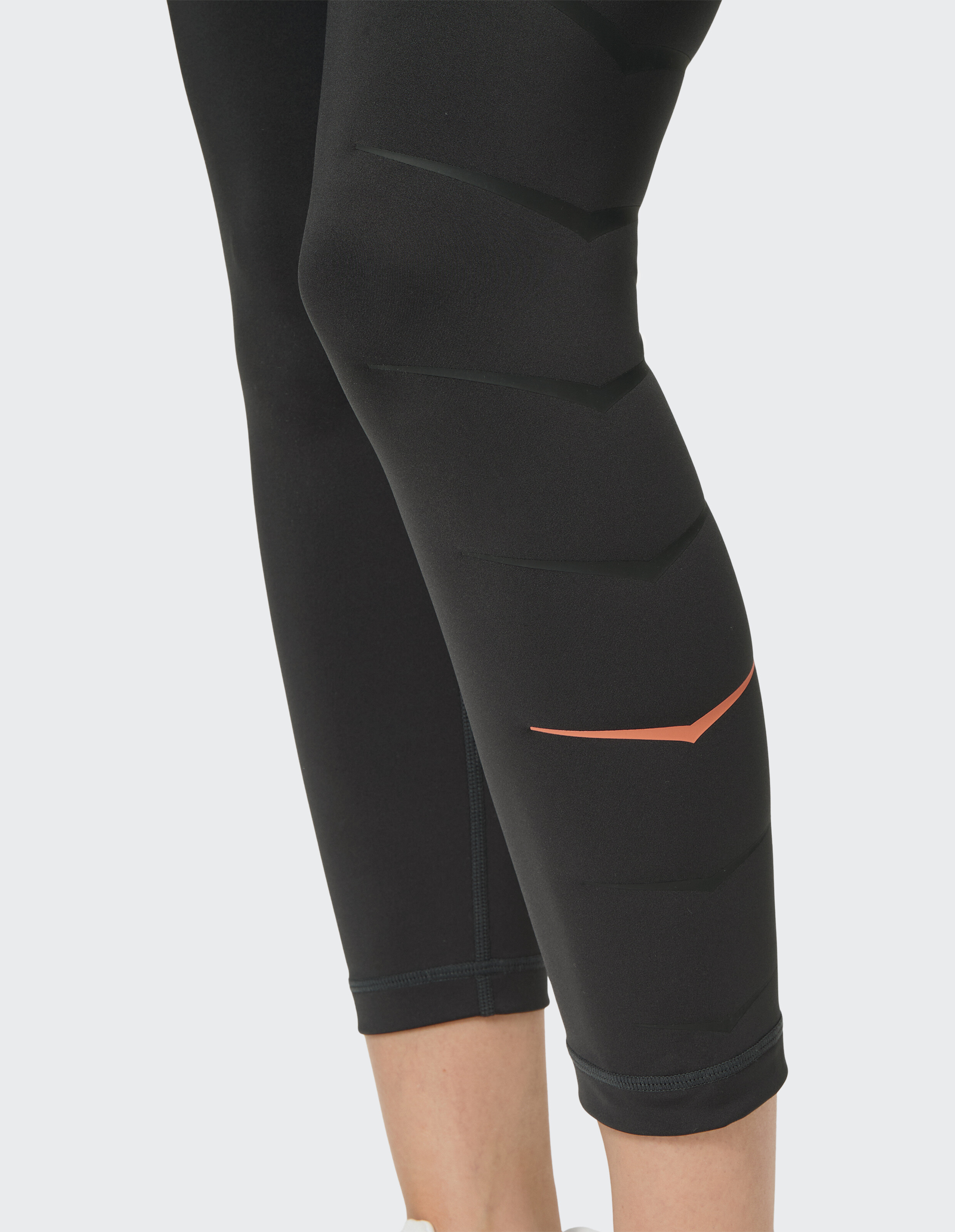 Nahaufnahme einer schwarzen Leggings mit strukturiertem Design und Korallenakzent für Freizeitkleidung.