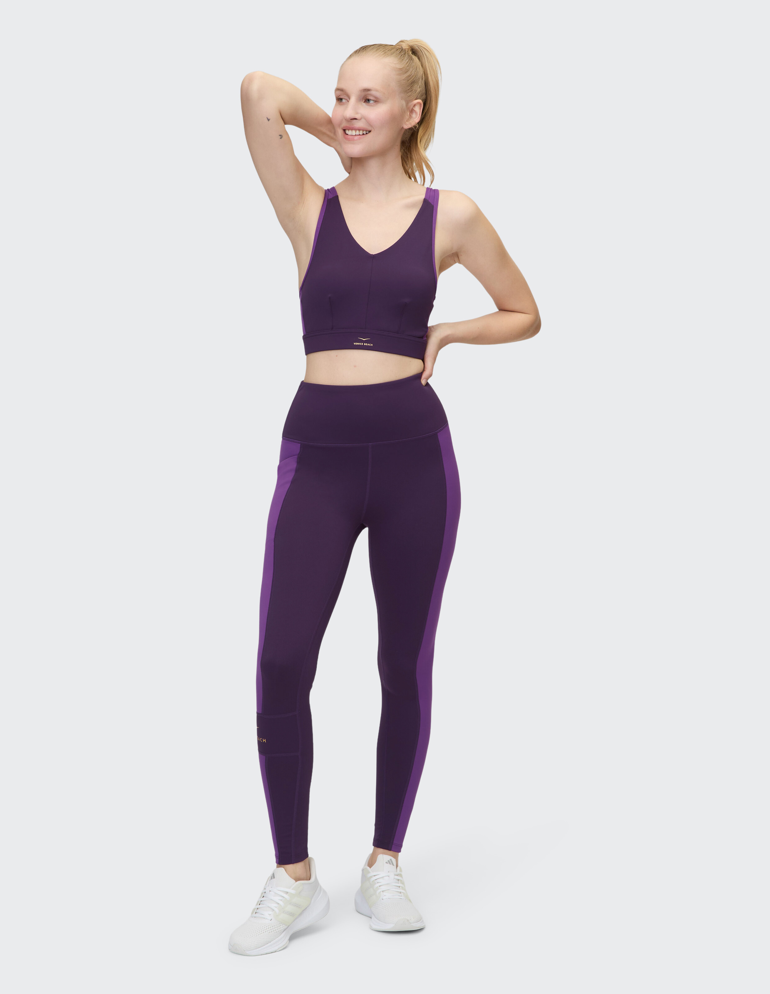 Das Model trägt einen lila Sport-BH und passende Leggings, perfekt für lässige Workouts.