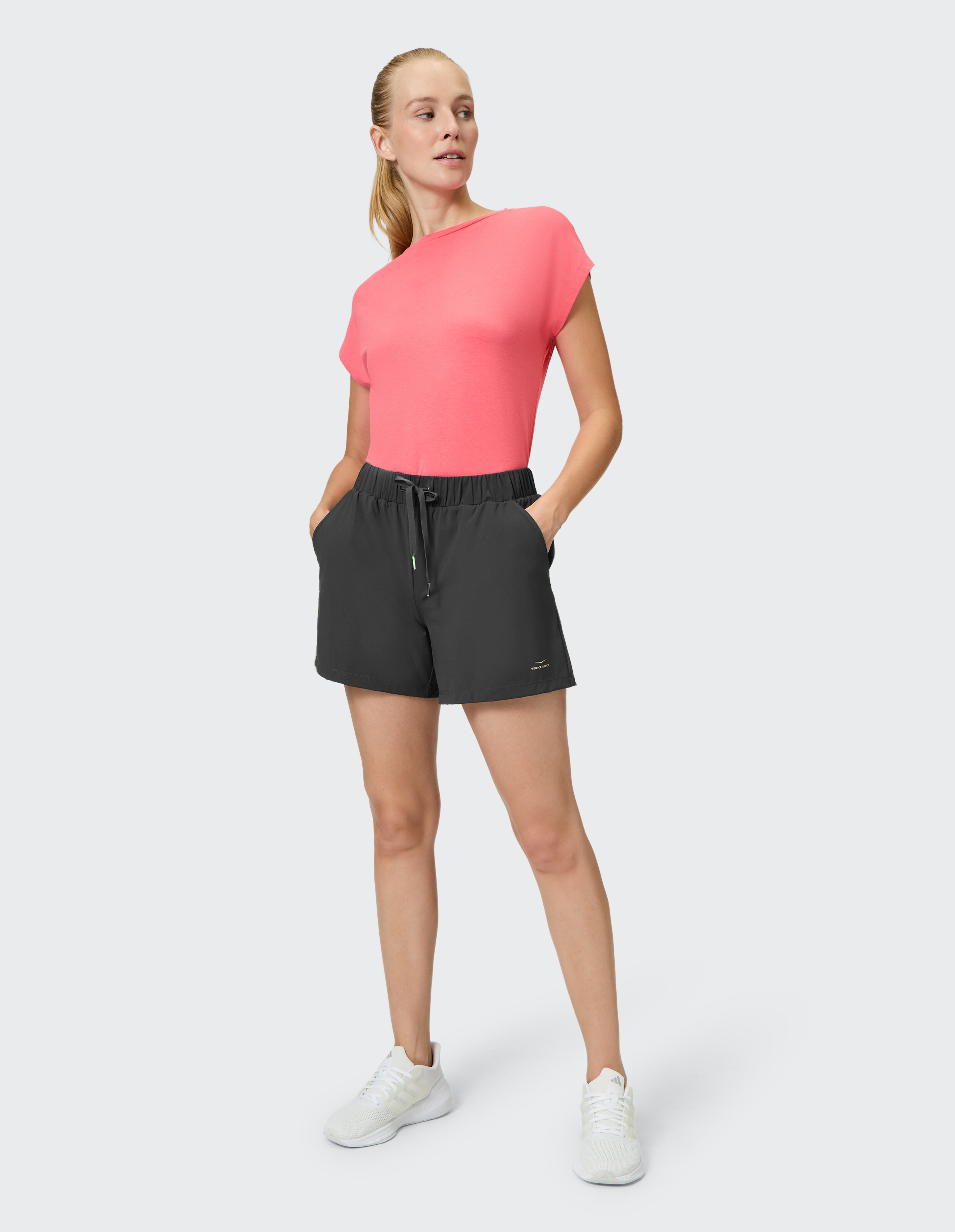 Frau in einem rosa Top und schwarzen Shorts, die einen lässigen Sommerstil präsentiert.