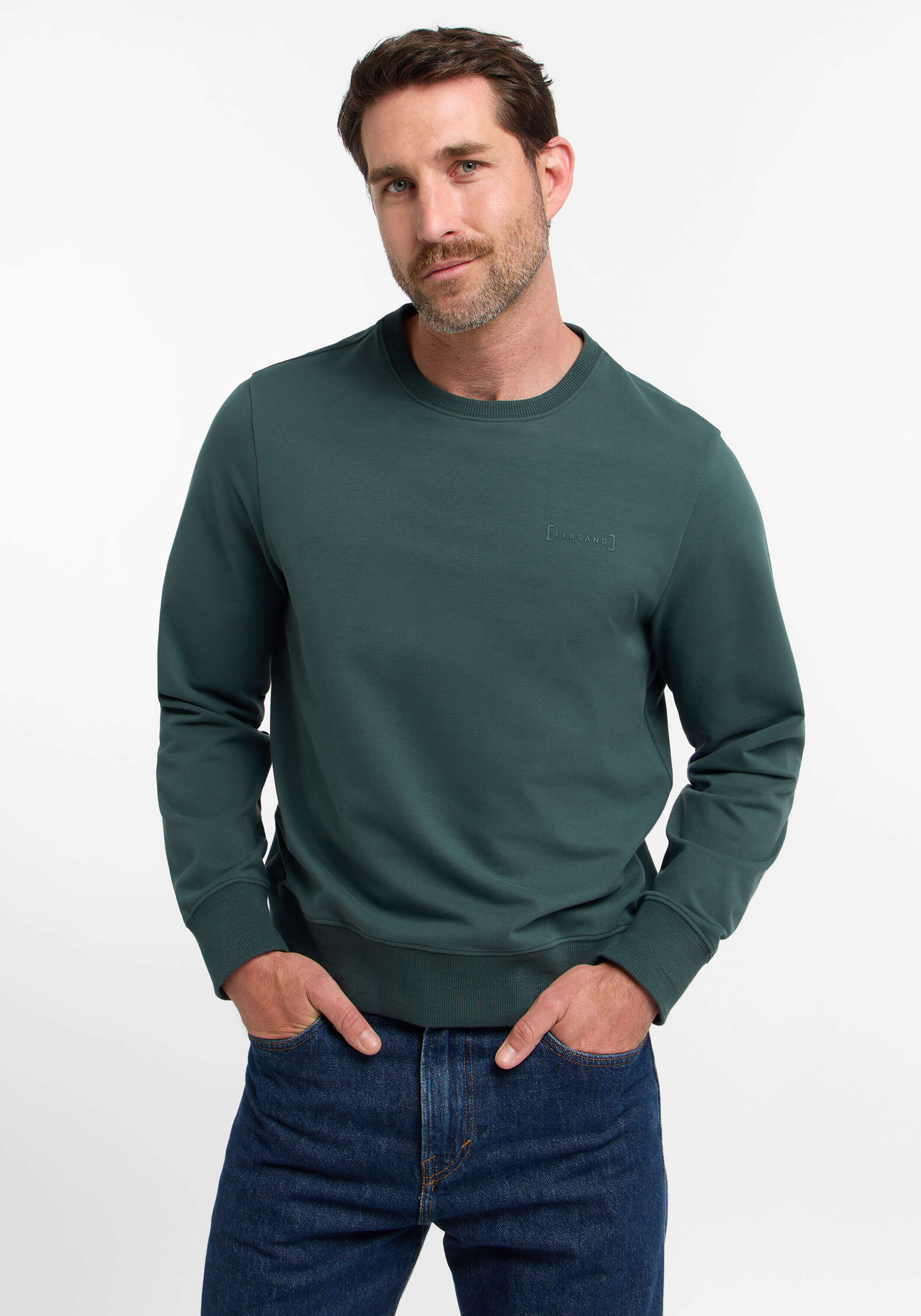 Mann trägt ein dunkelgrünes ELBSAND-Sweatshirt mit Rundhalsausschnitt für einen lässigen Alltagsstil.