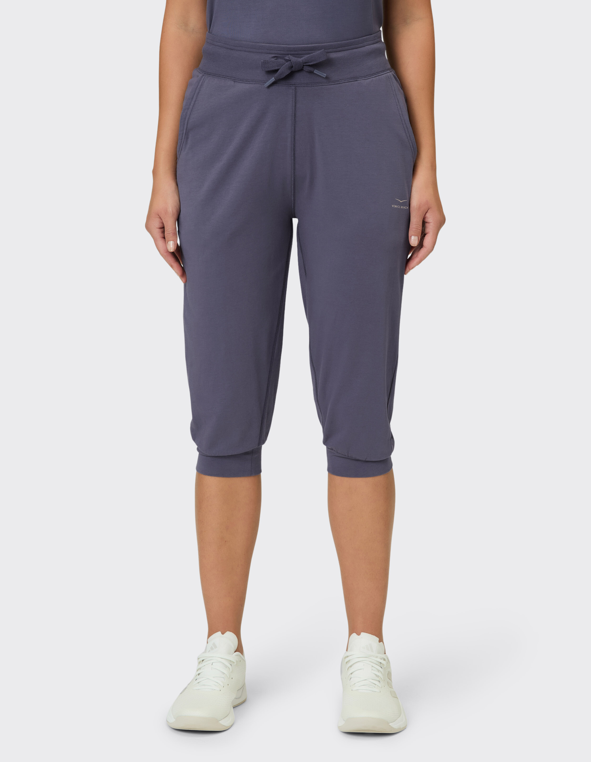 Frau trägt dunkelblaue, lässige Capri-Loungehose mit Kordelzug in der Taille.
