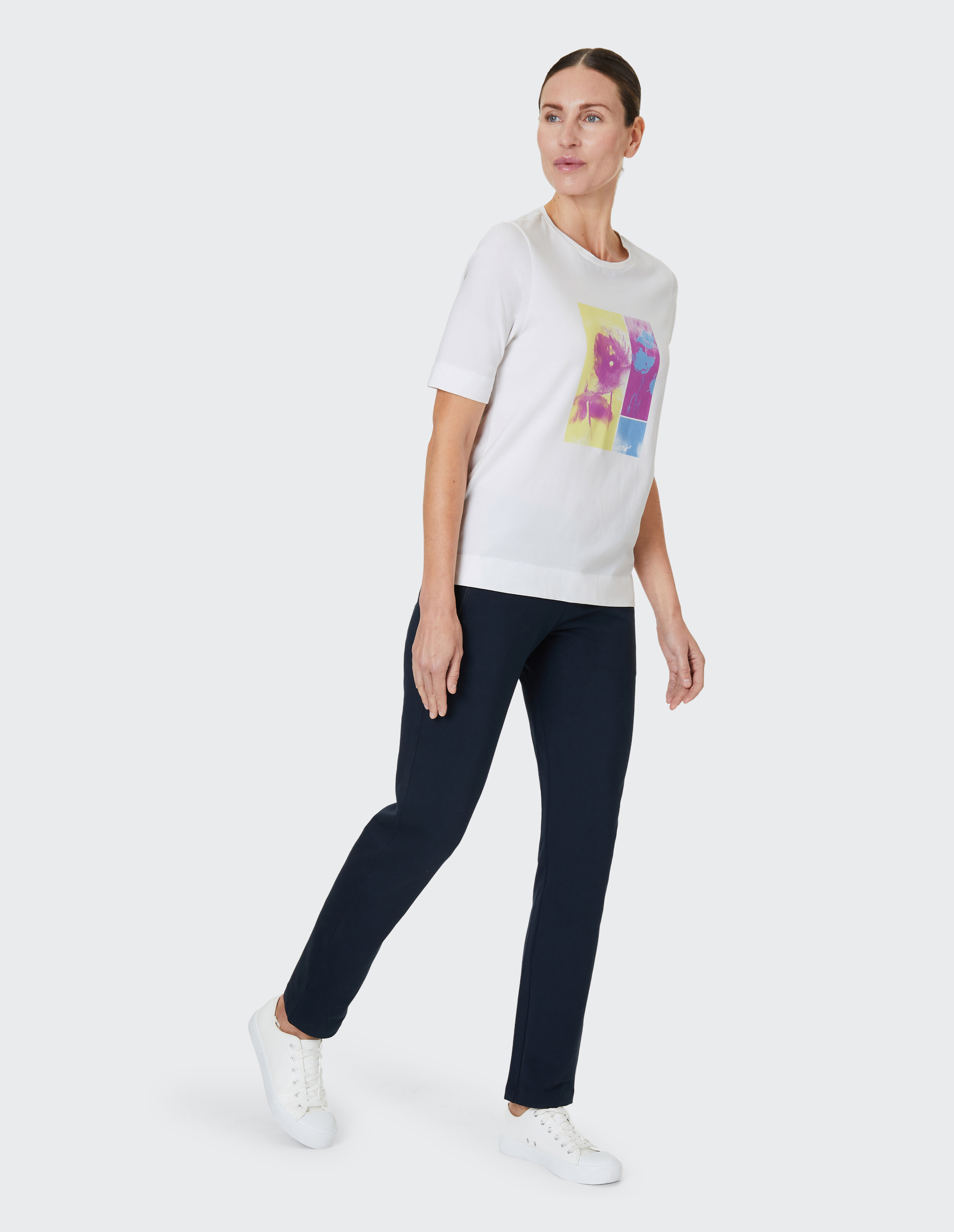 Weißes T-Shirt mit buntem Blumenprint in gelben und violetten Tönen auf der Vorderseite, das ein künstlerisches Design zeigt.