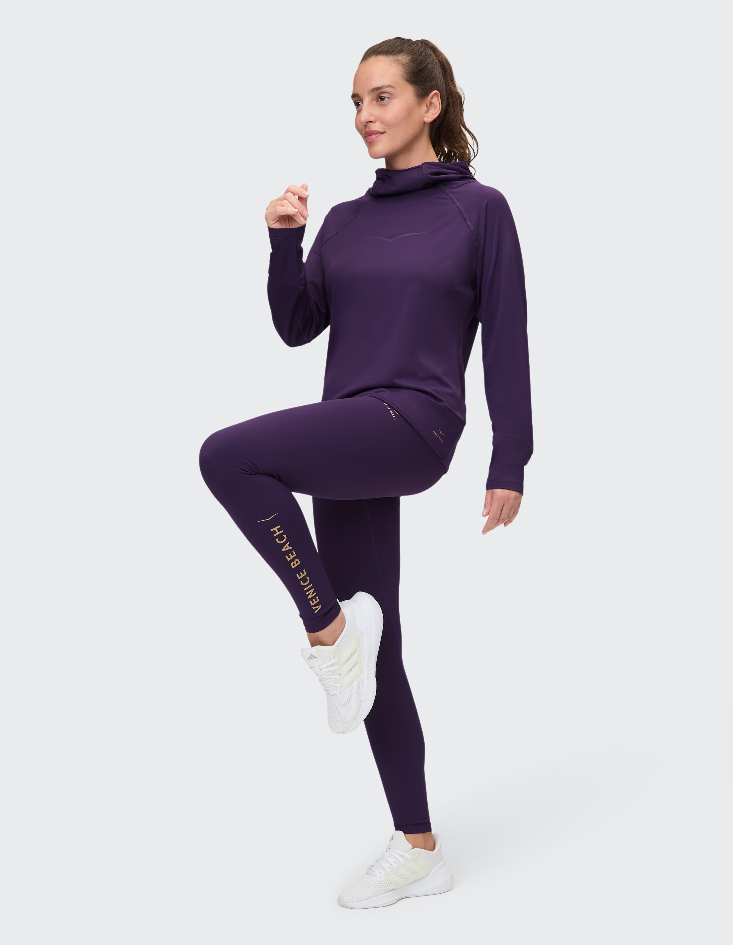 Frau trägt einen lila Kapuzenpullover und Leggings für lässige Sportkleidung.