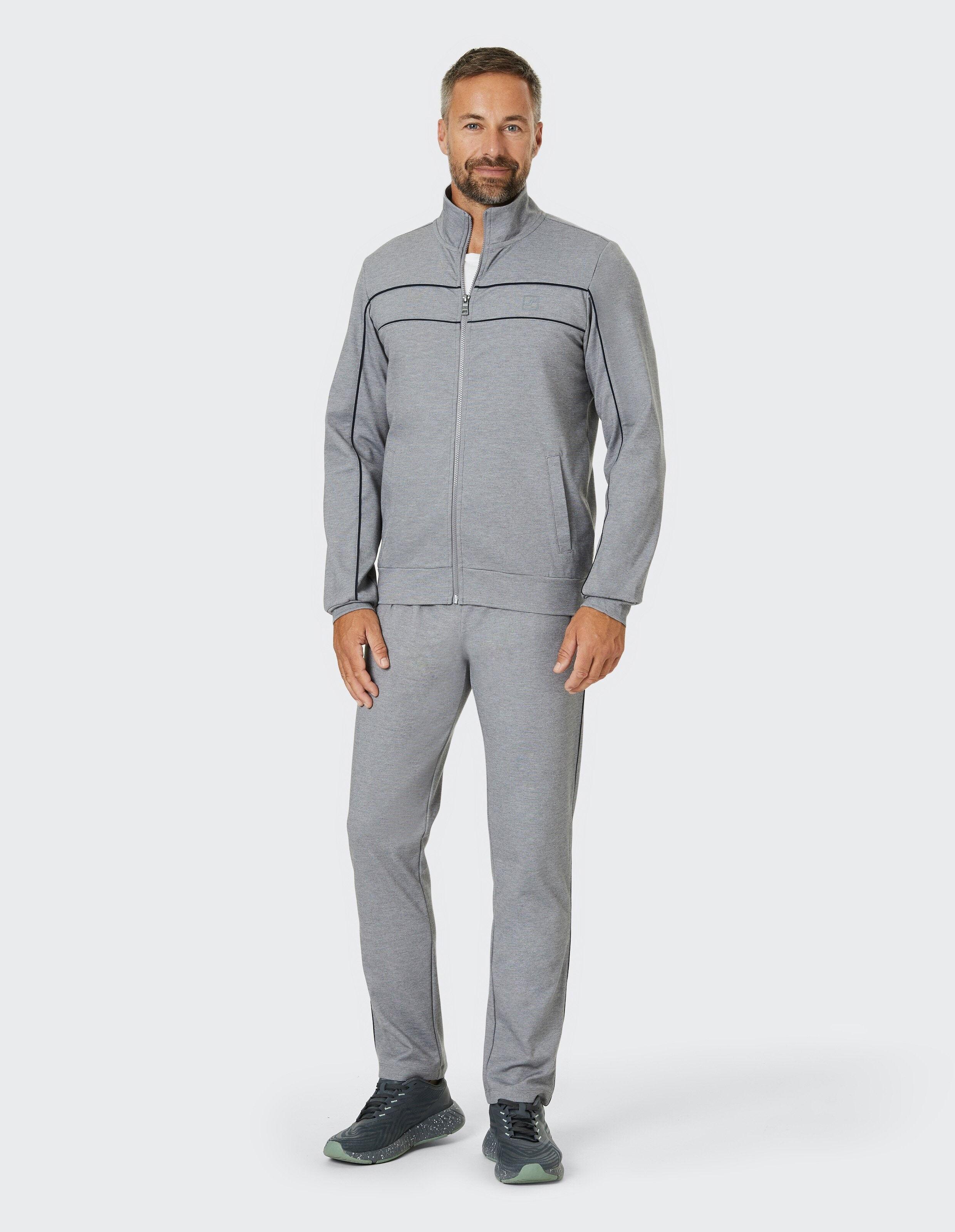Grauer Jogginganzug mit Stehkragen, durchgängigem Reißverschluss und blauen Zierstreifen, bestehend aus Jacke und Hose.
