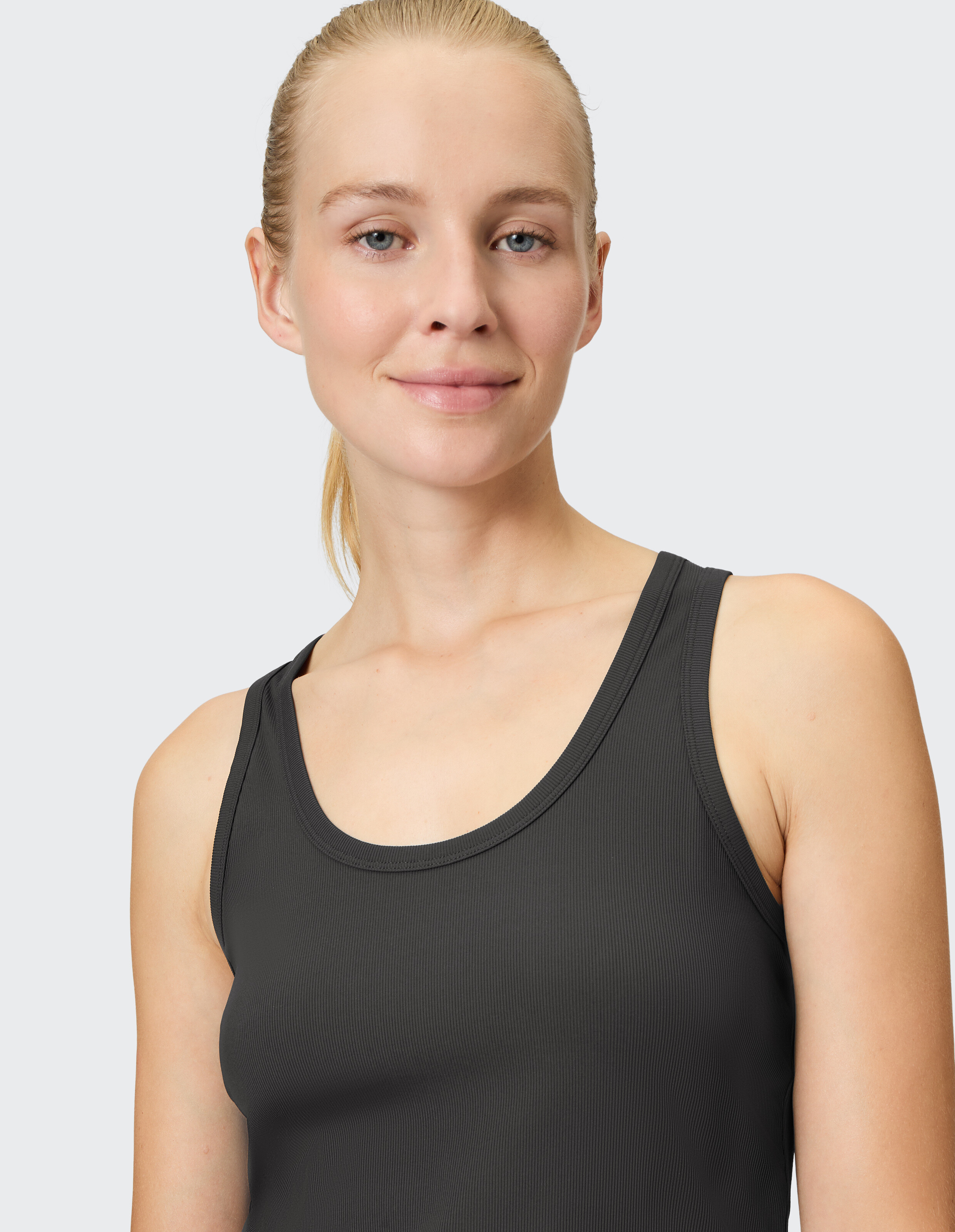 Nahaufnahme einer Frau, die ein schwarzes, geripptes Tanktop trägt und einen lässigen Stil unterstreicht.