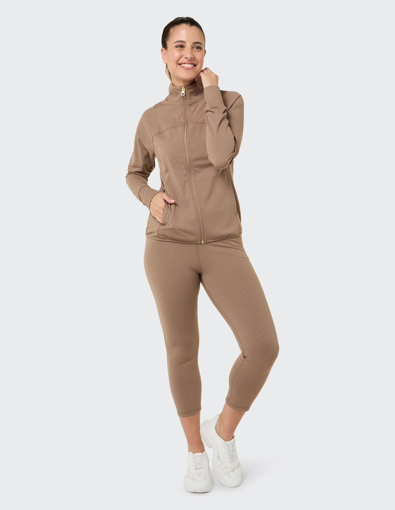 Frau in einer gemütlichen braunen Jacke mit Reißverschluss und passenden Leggings, perfekt für Freizeitkleidung.