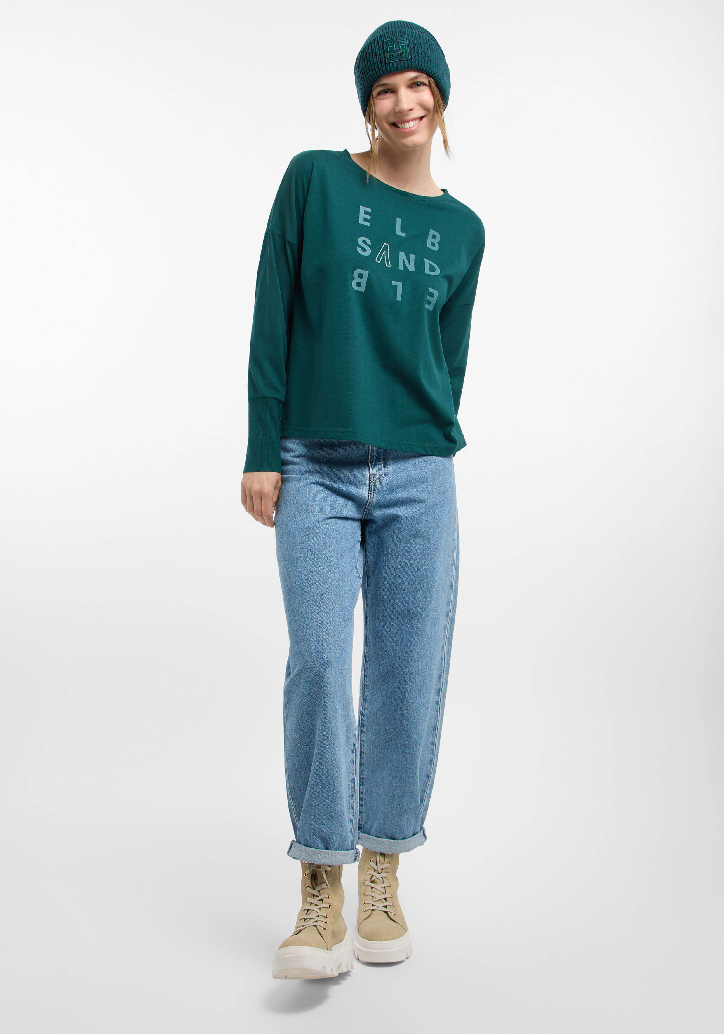Das Model trägt ein blaugrünes Langarmhemd und hellblaue Jeans, gestylt für lässigen Komfort.