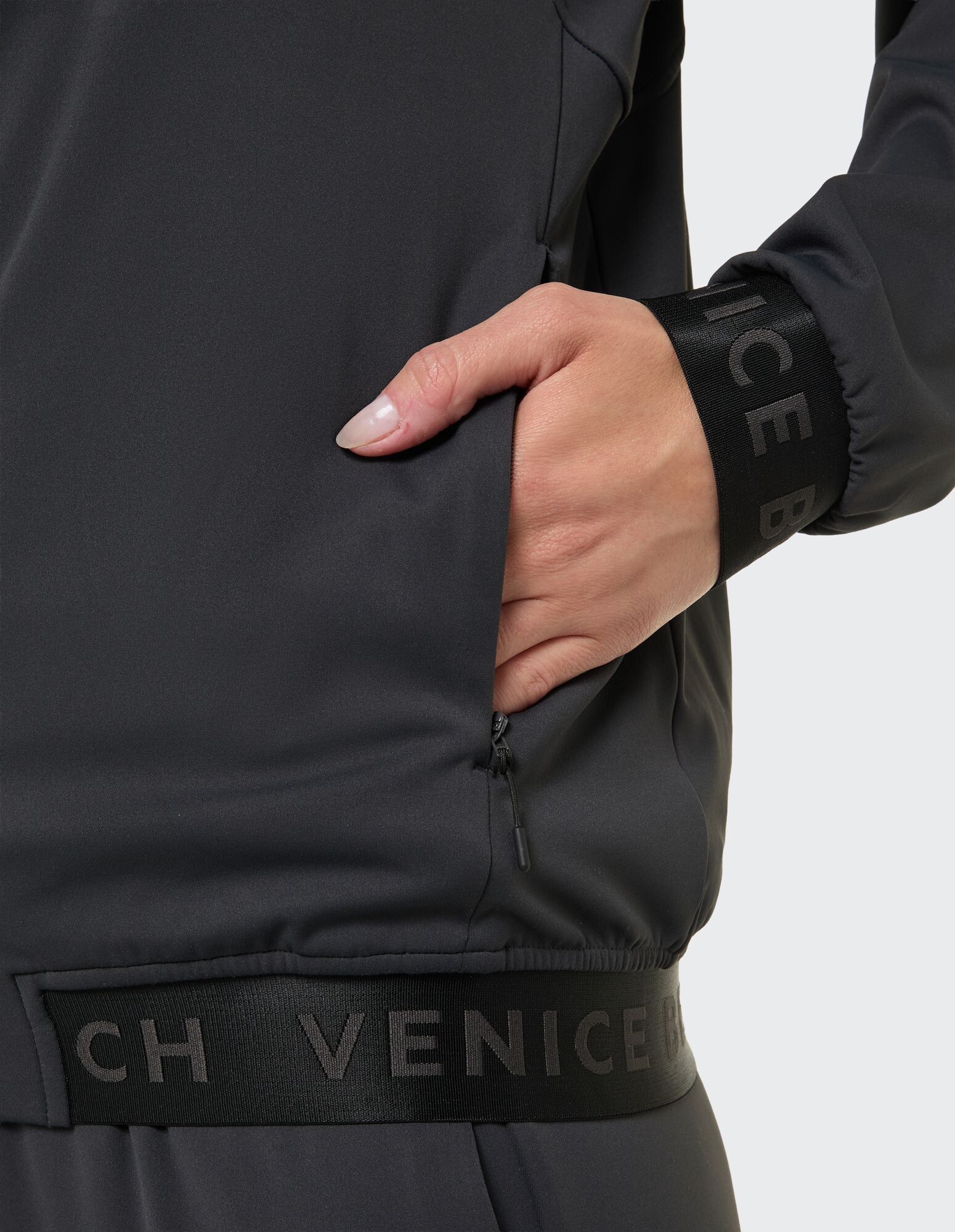 Nahaufnahme einer Frauenhand in einer dunkelgrauen Jackentasche mit Logodetails.