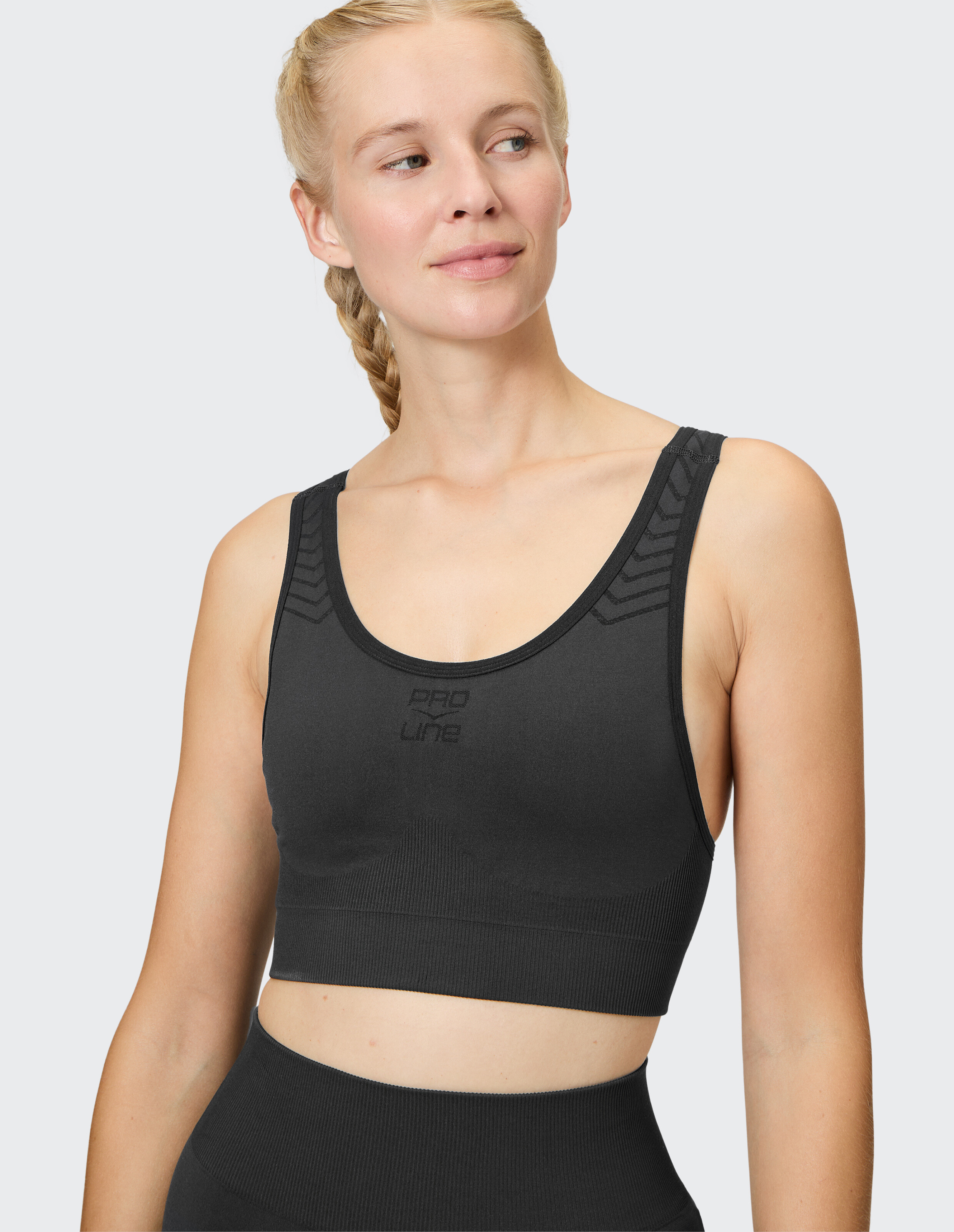 Frau trägt einen schwarzen Sport-BH „Venice Beach Top Miami“ für sportliche Freizeitkleidung.