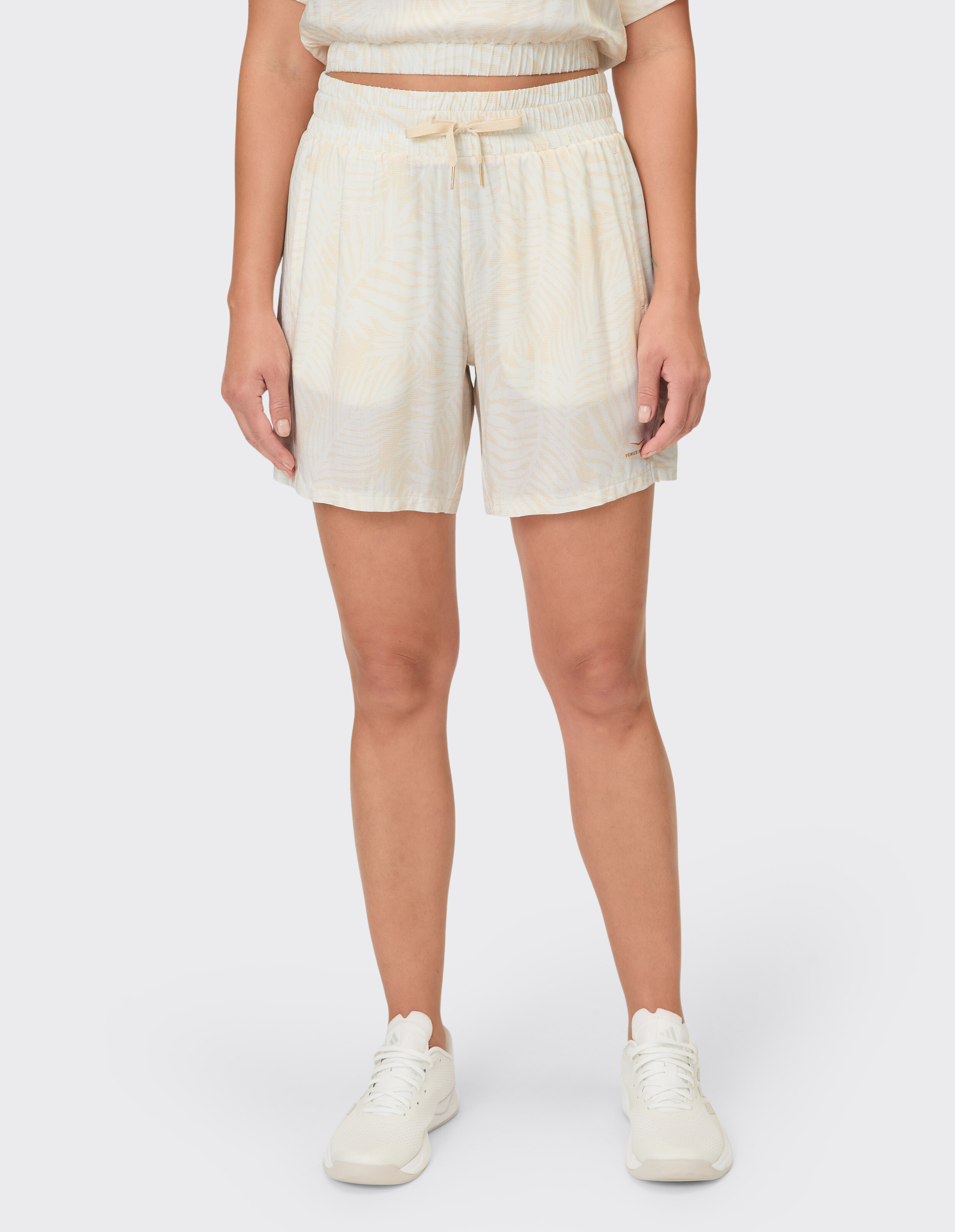 Frau trägt beige gemusterte, lässige Lounge-Shorts mit elastischem Kordelzug in der Taille.