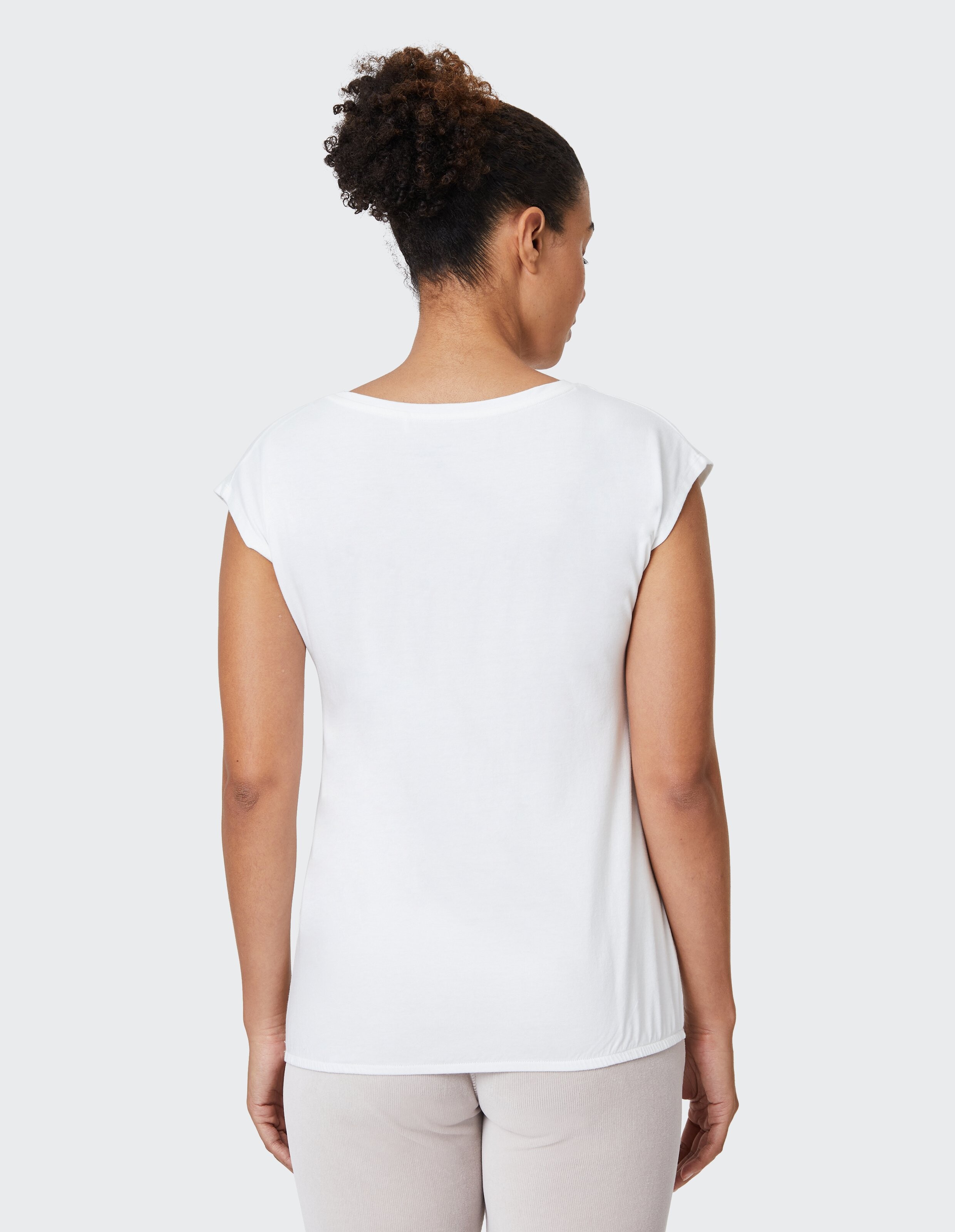 Frau trägt ein weißes Freizeit-T-Shirt mit Flügelärmeln, Rückansicht, Studioaufnahme.