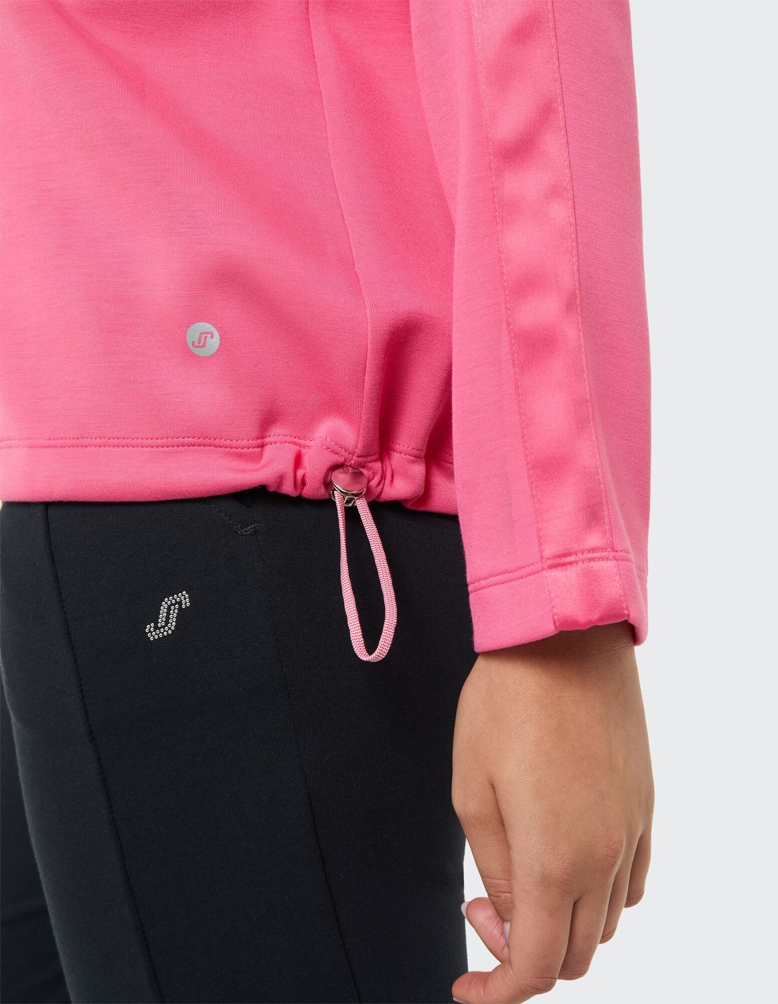 Nahaufnahme eines rosa Freizeitoberteils mit verstellbarem Saum und schwarzen Leggings.