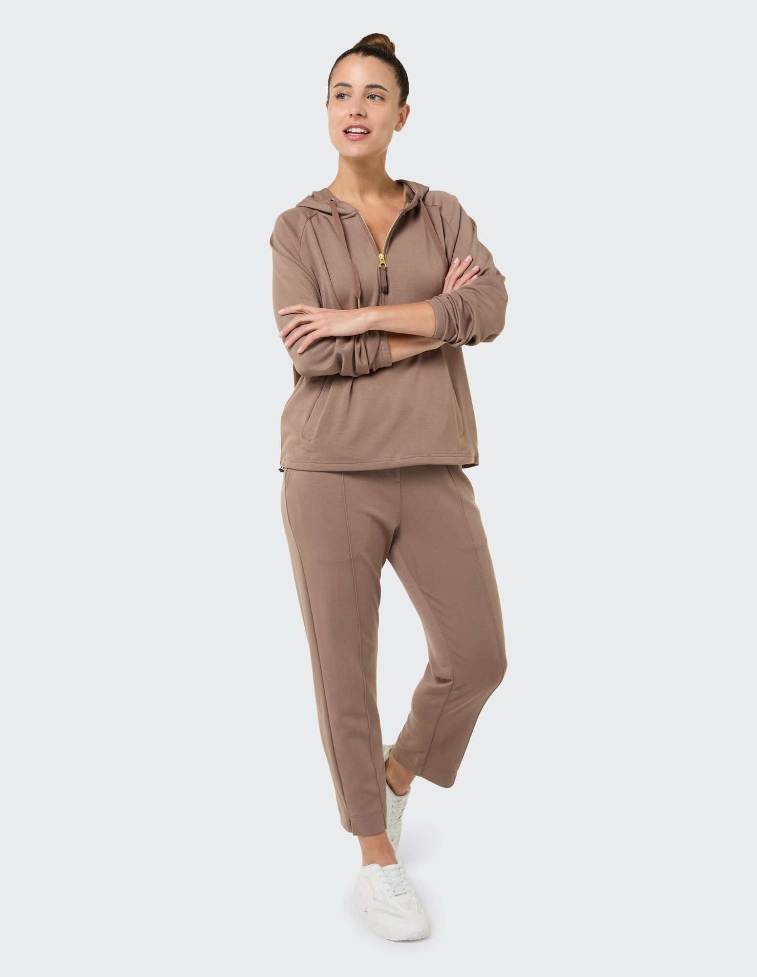 Kuscheliger brauner Kapuzenpullover und passende Hose für Freizeitkleidung, kombiniert mit weißen Turnschuhen.