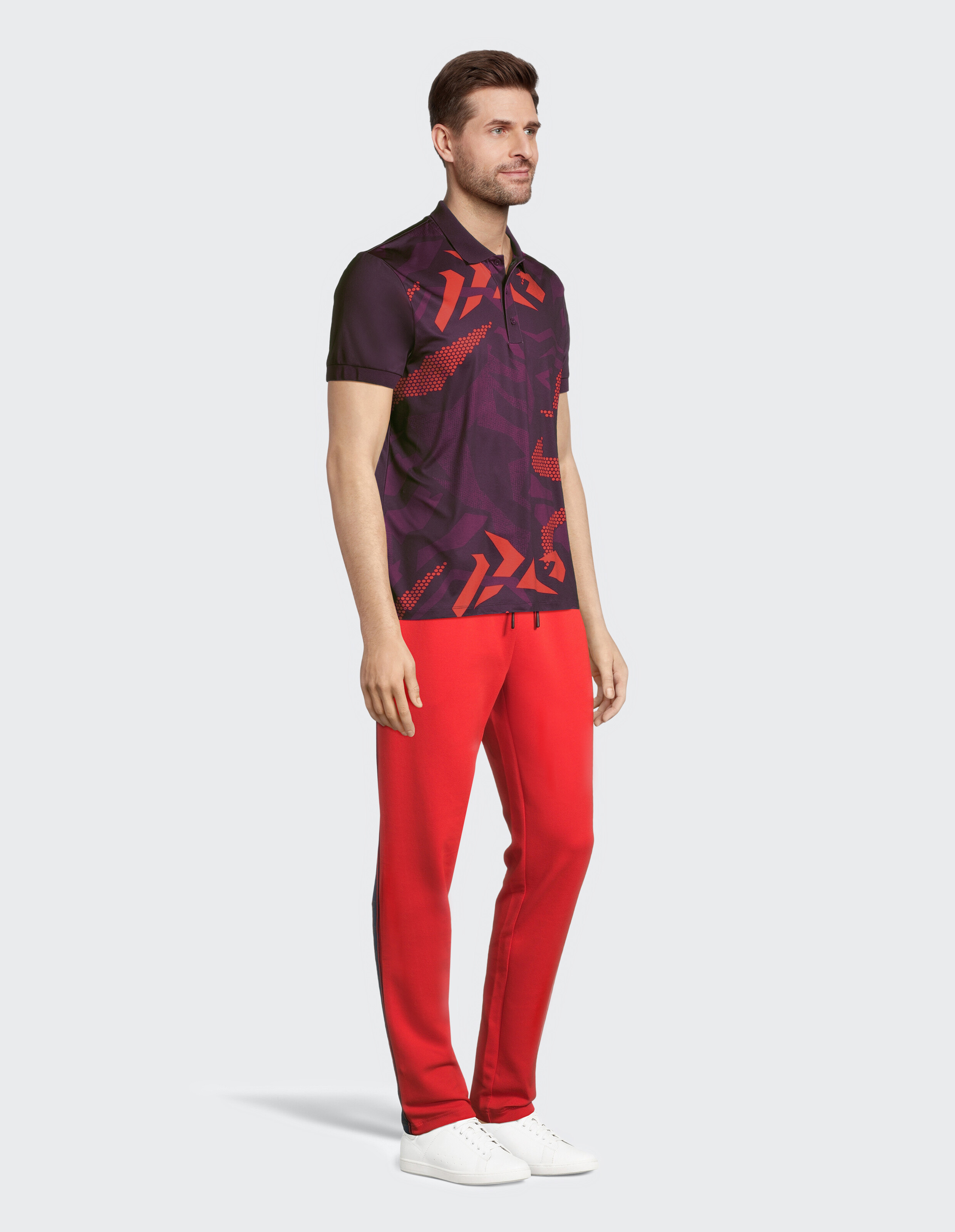 Mann trägt ein gemustertes lila Poloshirt und eine rote Freizeit-Jogginghose.