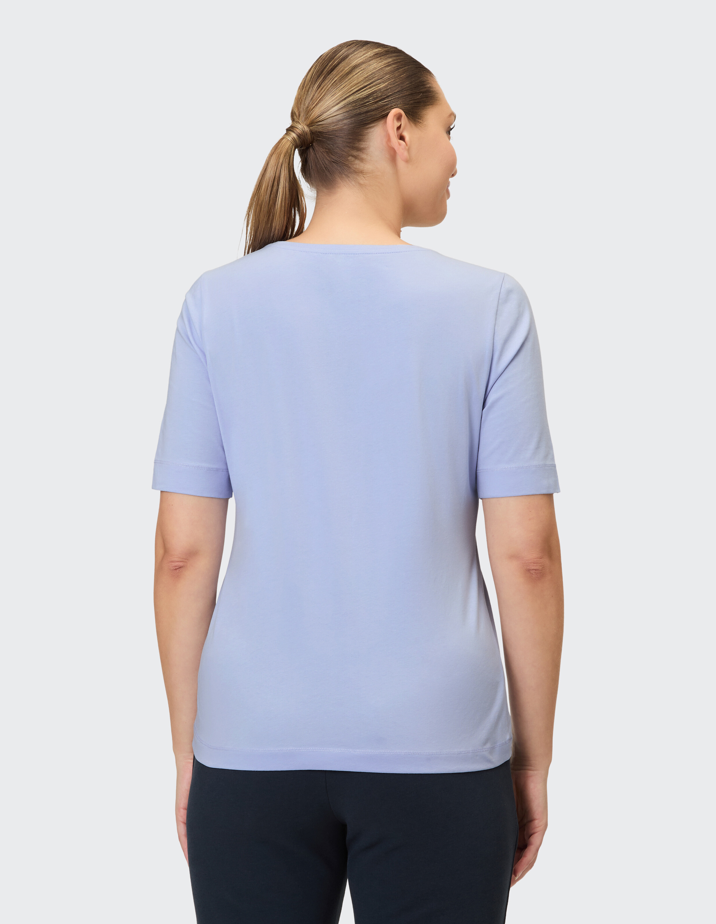 Eine Frau trägt eine hellviolette, kurzärmelige Rundhals-T-Shirt.