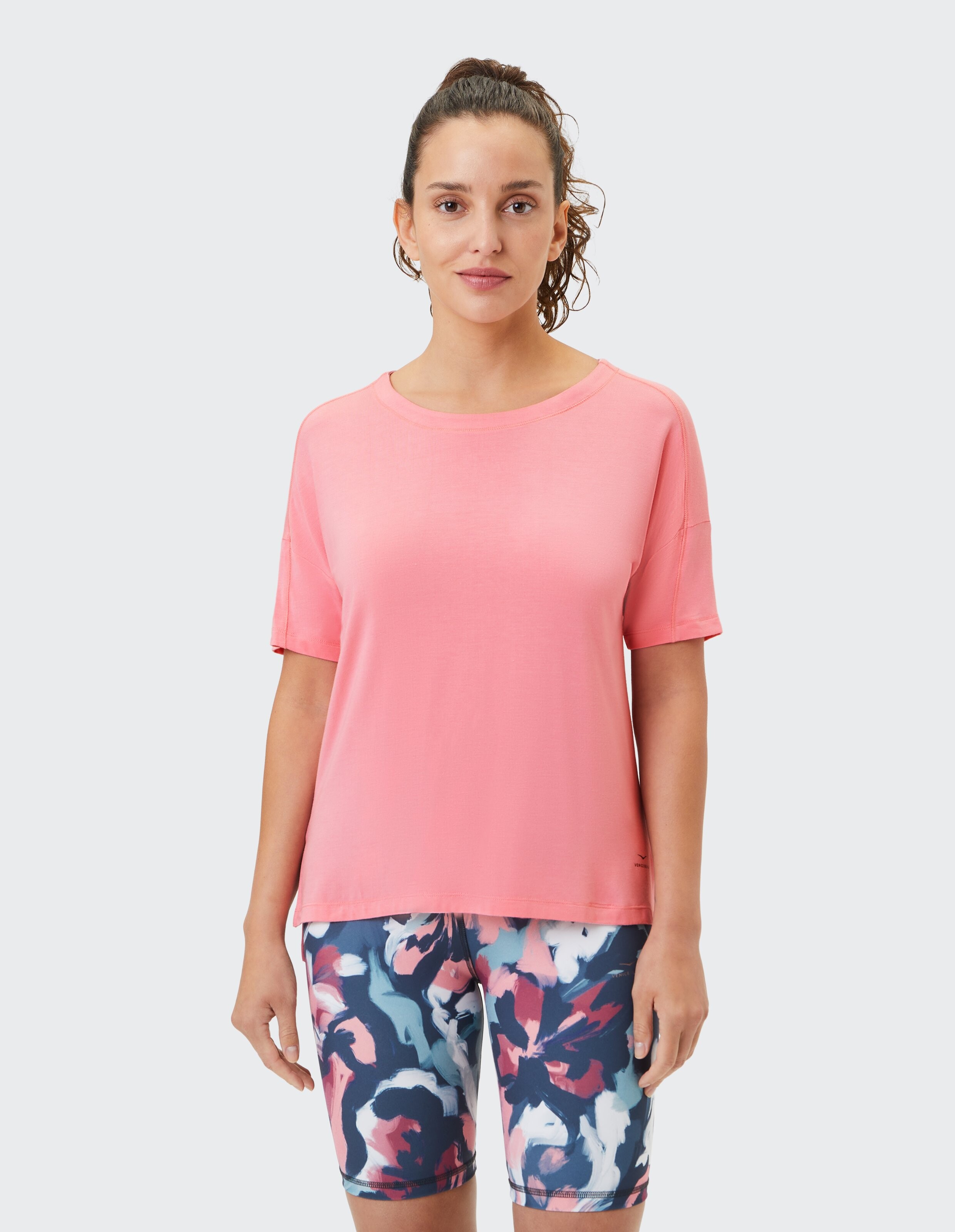 Frau trägt ein lässiges rosa T-Shirt und gemusterte Shorts für einen bequemen Lounge-Look.