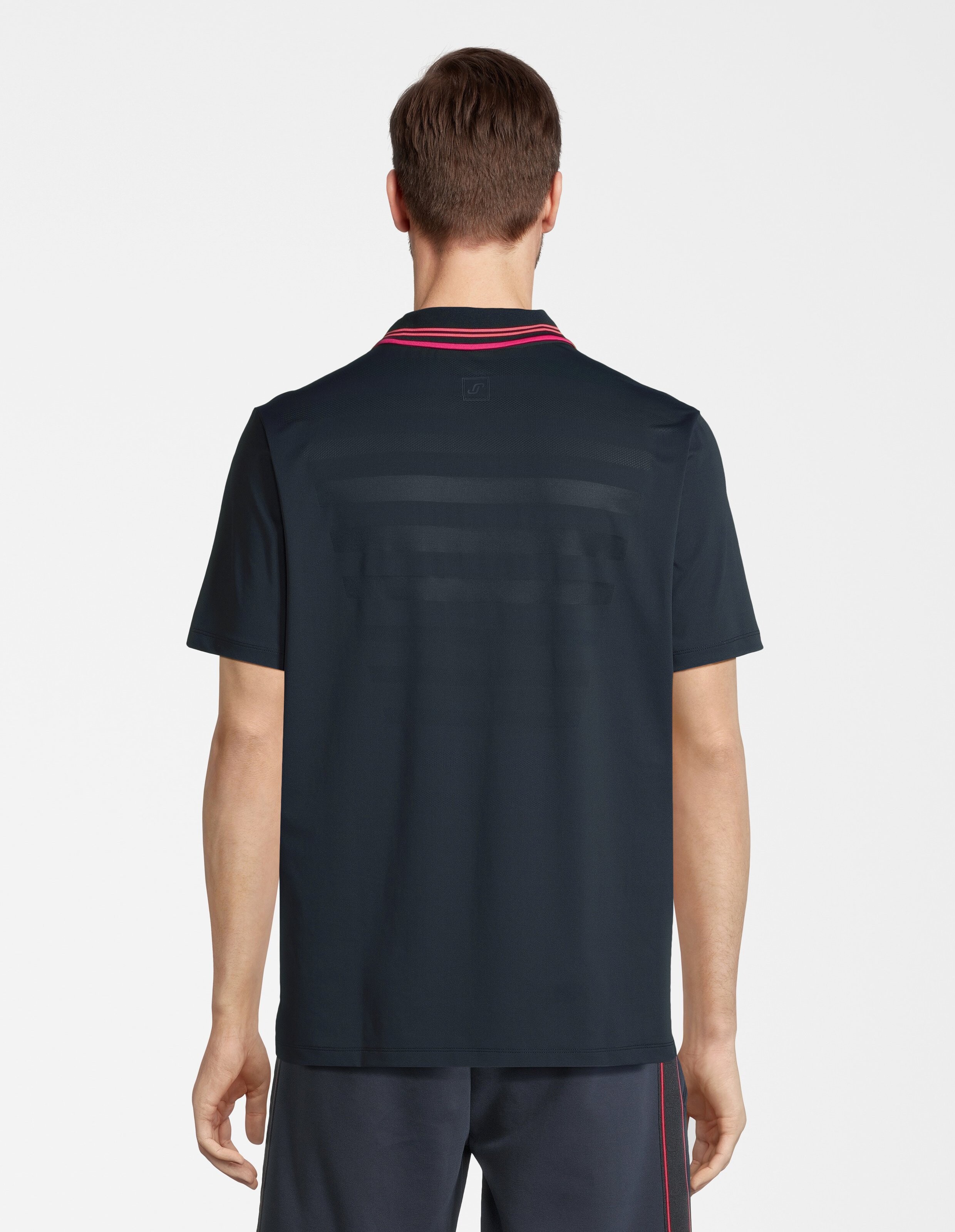 Eine Person trägt ein dunkelblaues Poloshirt mit roten Streifen am Kragen, von hinten fotografiert vor weißem Hintergrund.