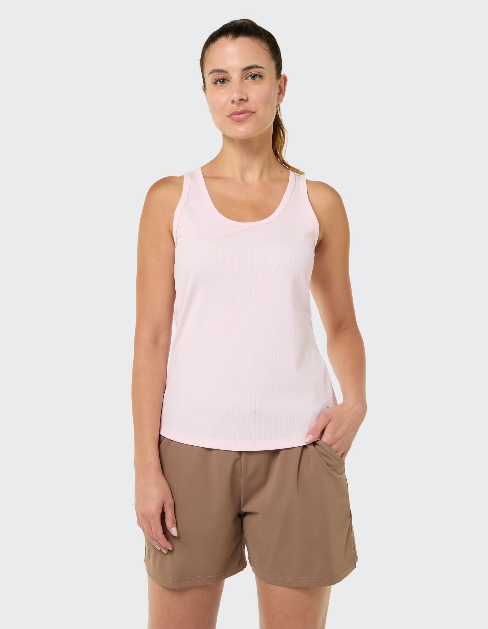 Hellrosa Tanktop gepaart mit braunen Freizeitshorts für bequemen Tragekomfort.