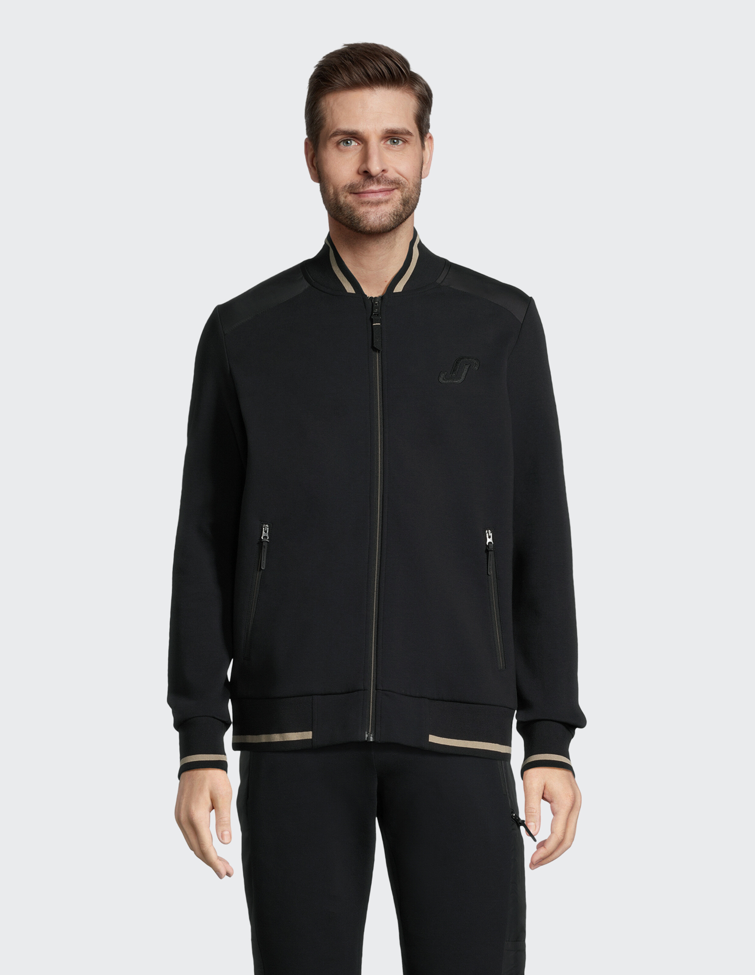 Mann trägt eine schwarze, lässige Bomberjacke mit beigem Besatz für einen gemütlichen, klassischen Look.