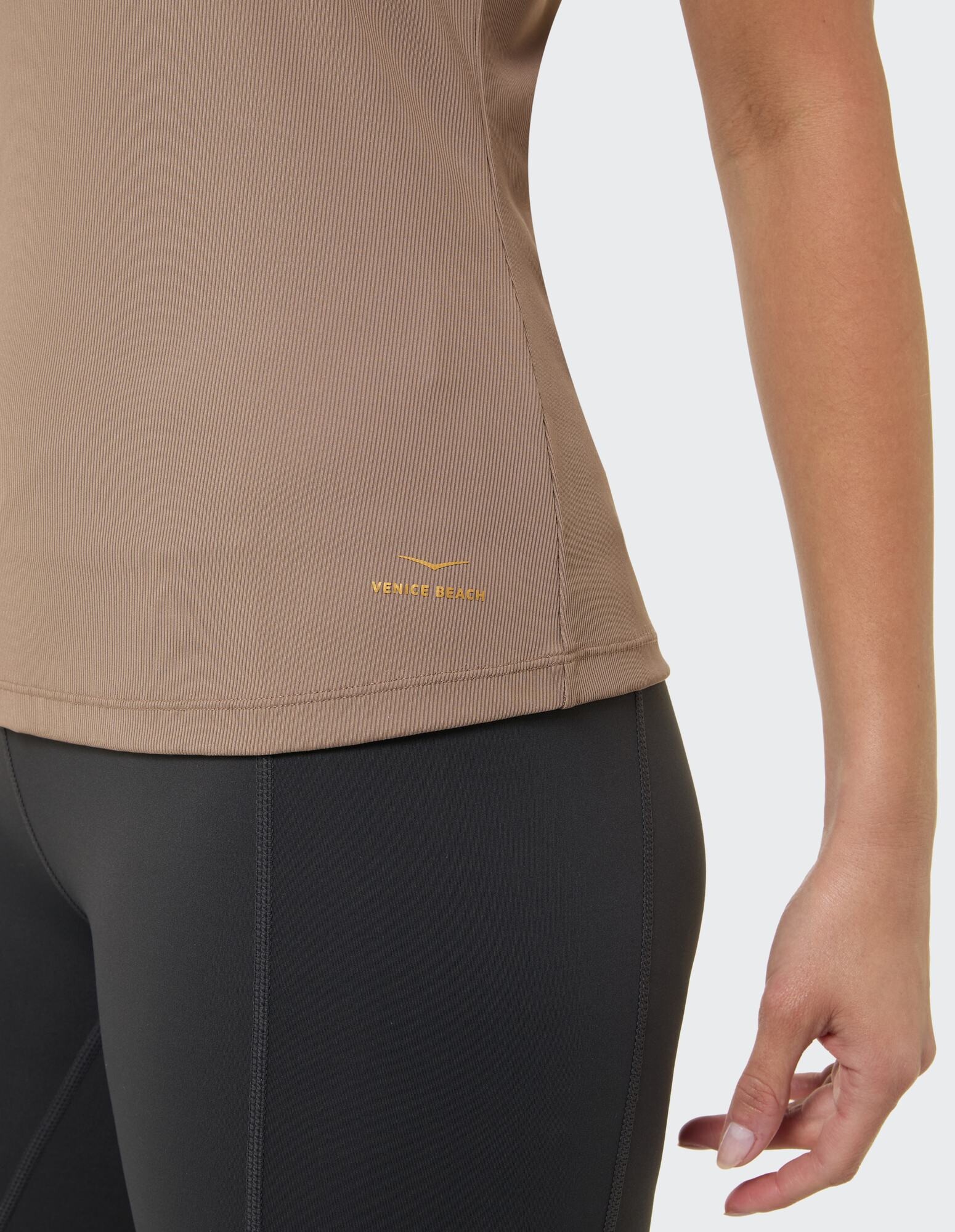 Nahaufnahme eines gerippten braunen Oberteils gepaart mit schwarzen Leggings, ideal für Freizeitkleidung.