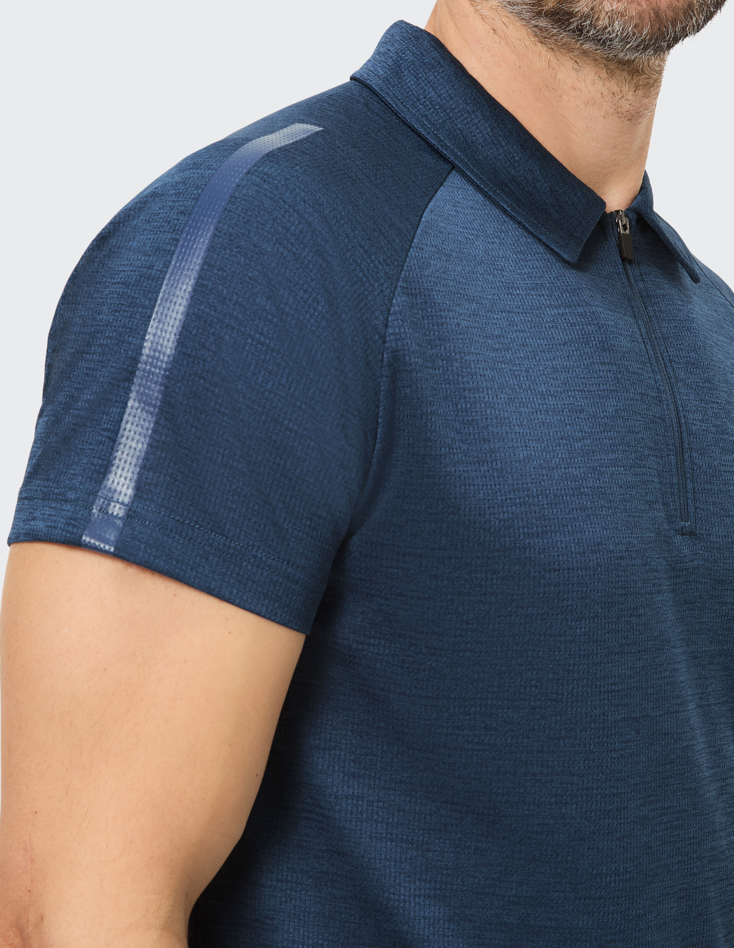Mann in einem dunkelblauen Polo-Shirt mit kurzen Ärmeln und Reißverschluss, zeigt Halbansicht von Schulter und Torso.