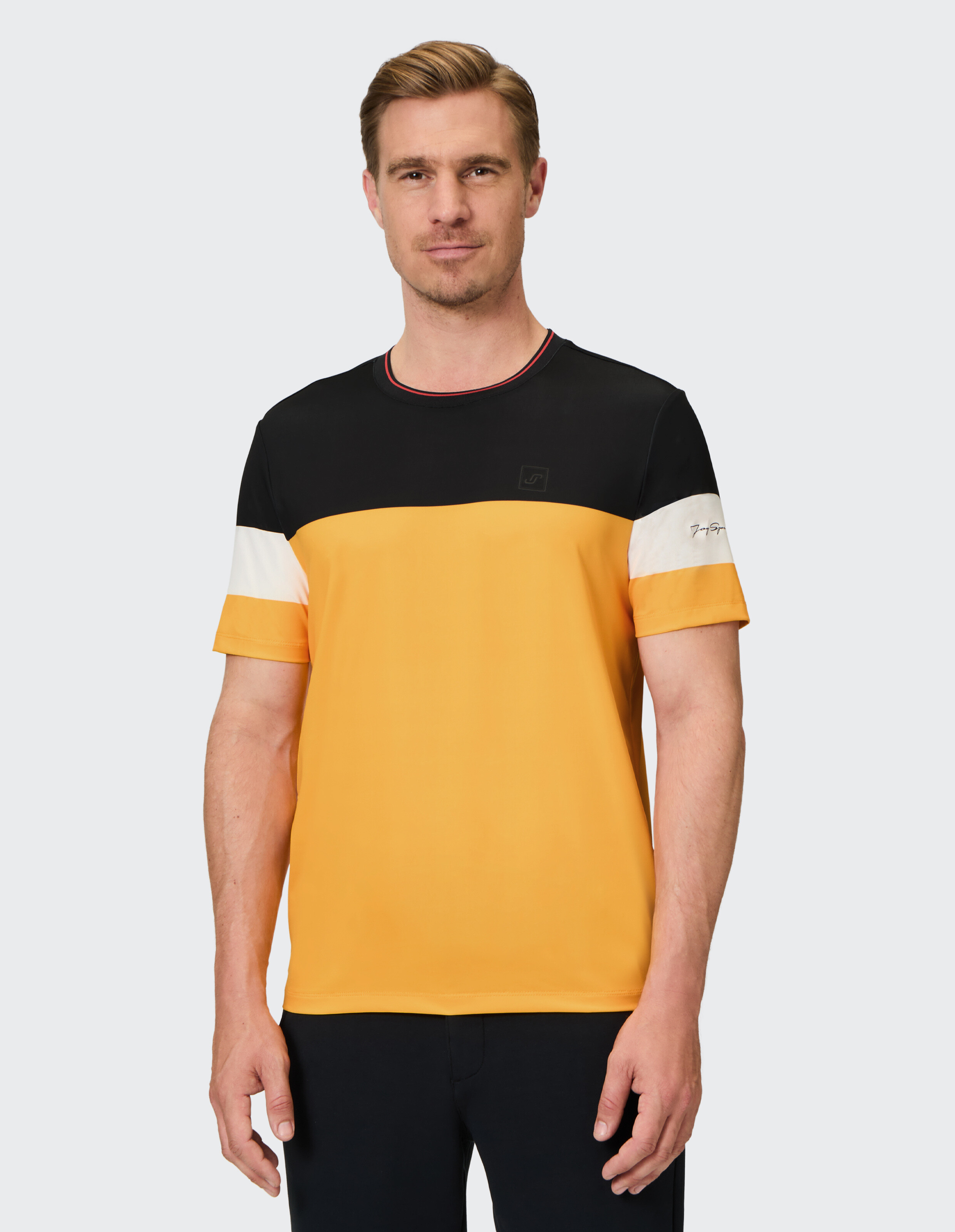 Mann trägt ein lässiges Farbblock-T-Shirt in Gelb, Schwarz und Weiß.