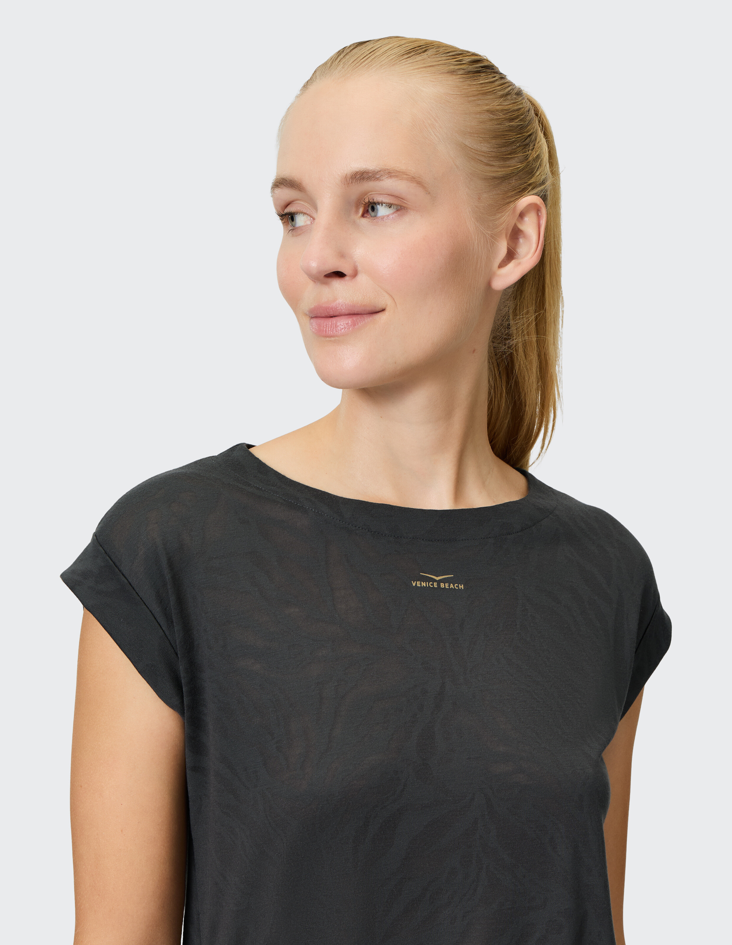Frau trägt ein schwarzes Kurzarm-Top mit dezentem Muster, ideal für Freizeitkleidung.