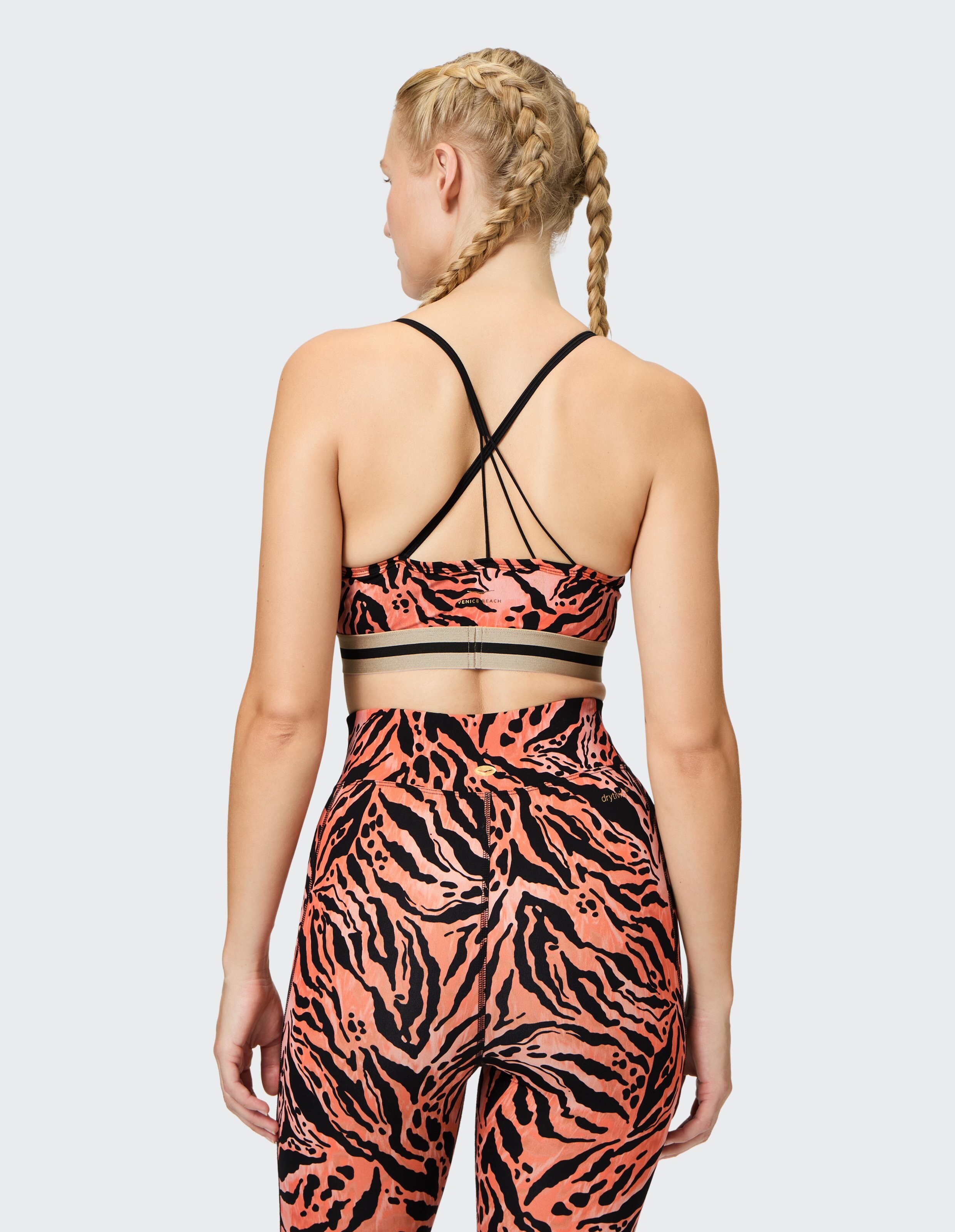 Rückansicht einer Frau in einem rosa-schwarzen Sport-BH mit Tigermuster und Leggings.