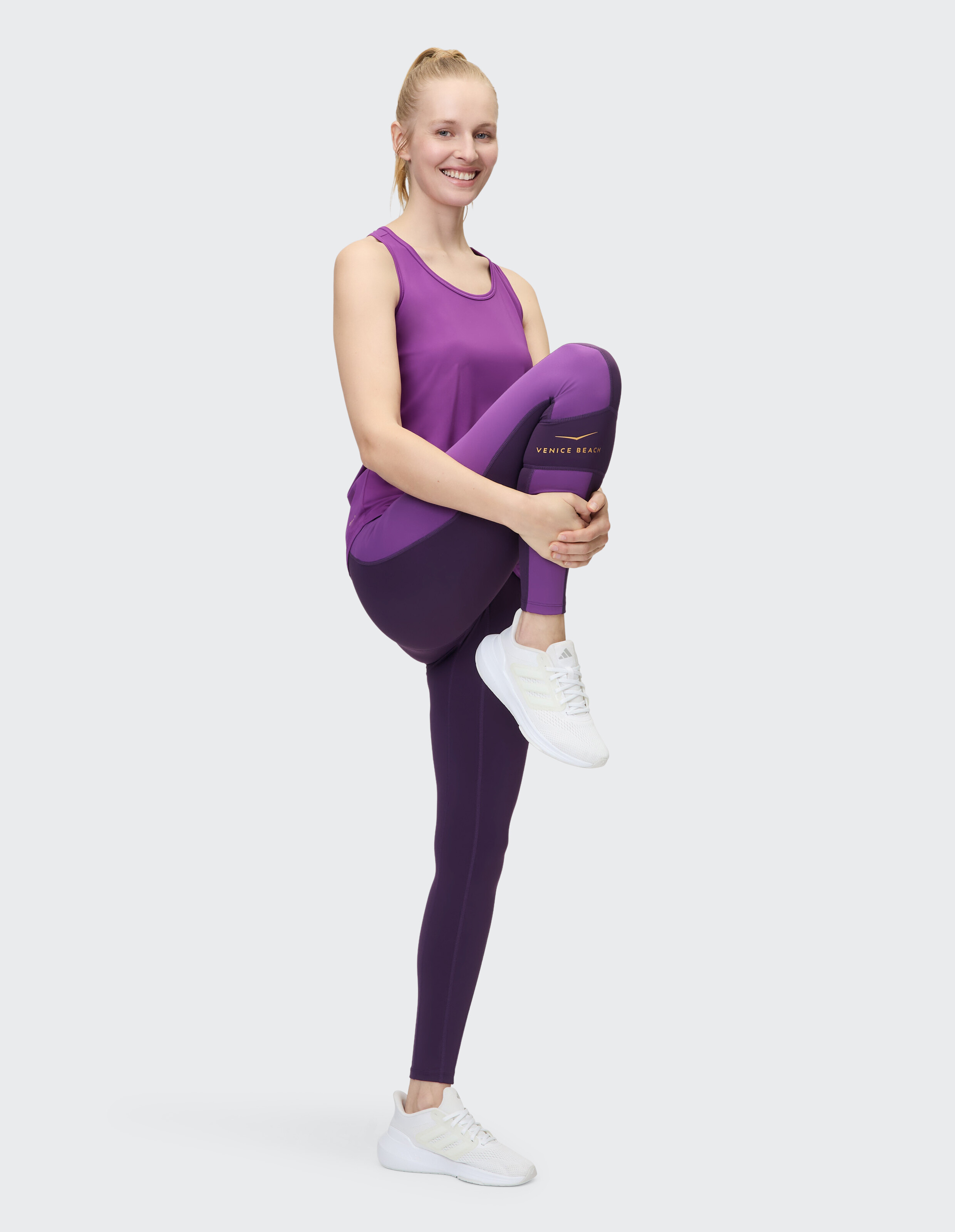 Frau in lila Tanktop und Leggings präsentiert lässige Sportkleidung.