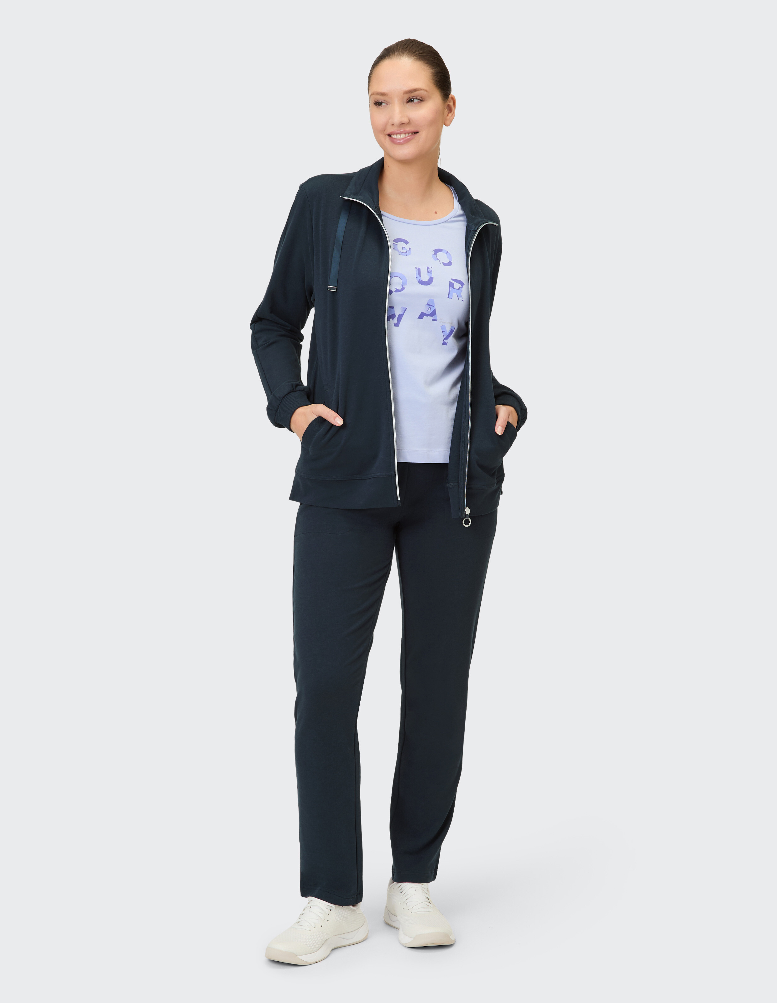 Frau in marineblauer Freizeitkleidung mit Reißverschlussjacke und grafischem T-Shirt, perfekt zum Entspannen.