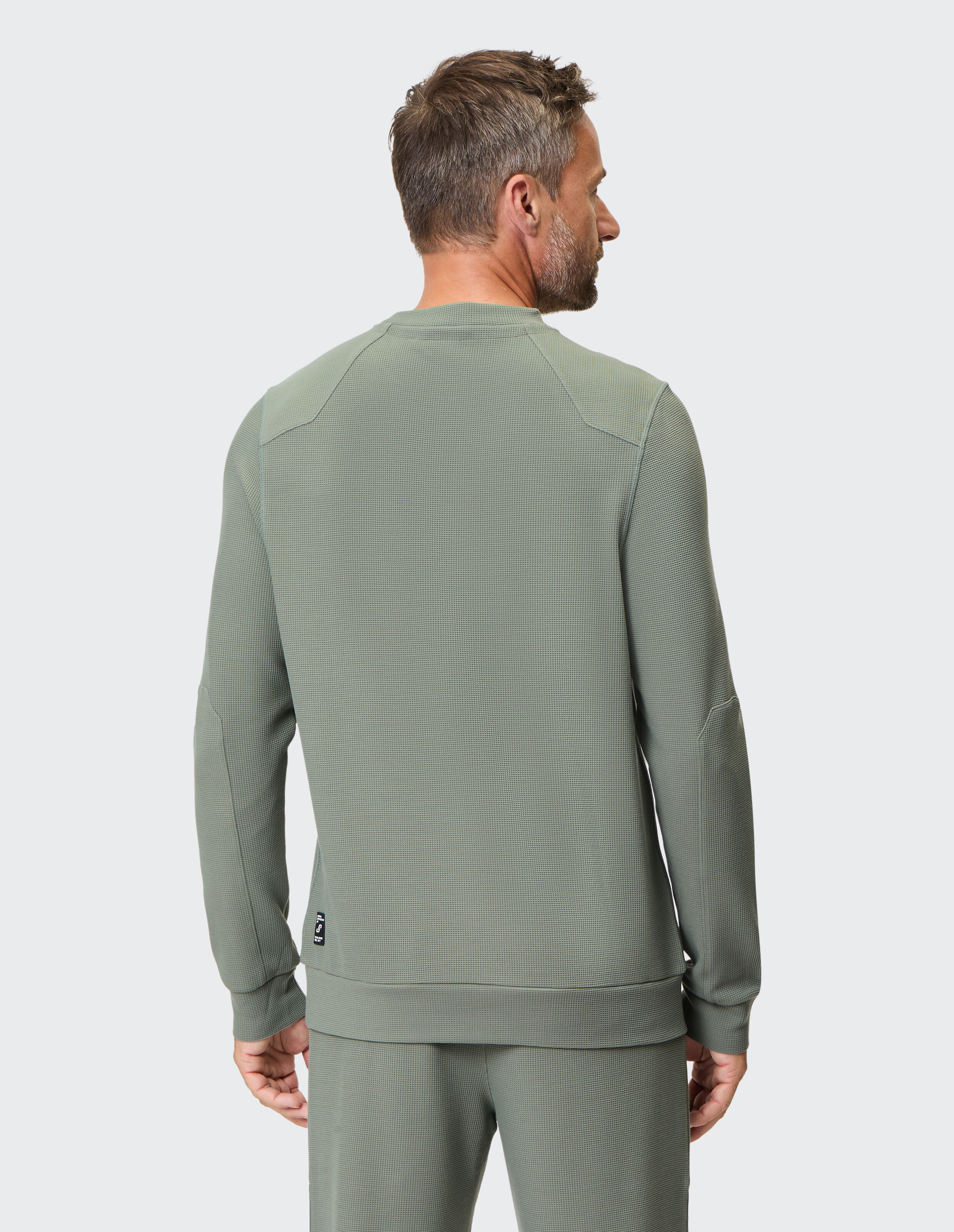 Grauer Pullover mit Rundhalsausschnitt und langen Ärmeln, gefertigt aus strukturiertem Stoff mit dezentem, geometrischem Muster.