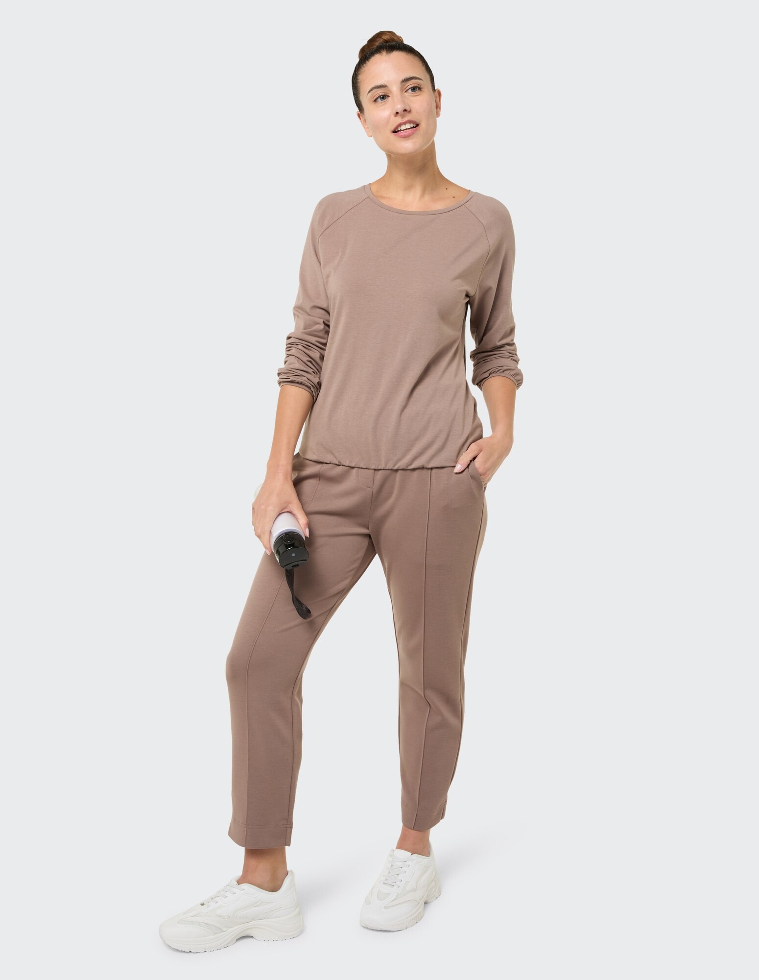 Frau in gemütlicher brauner Freizeitkleidung mit langen Ärmeln und Jogginghose.