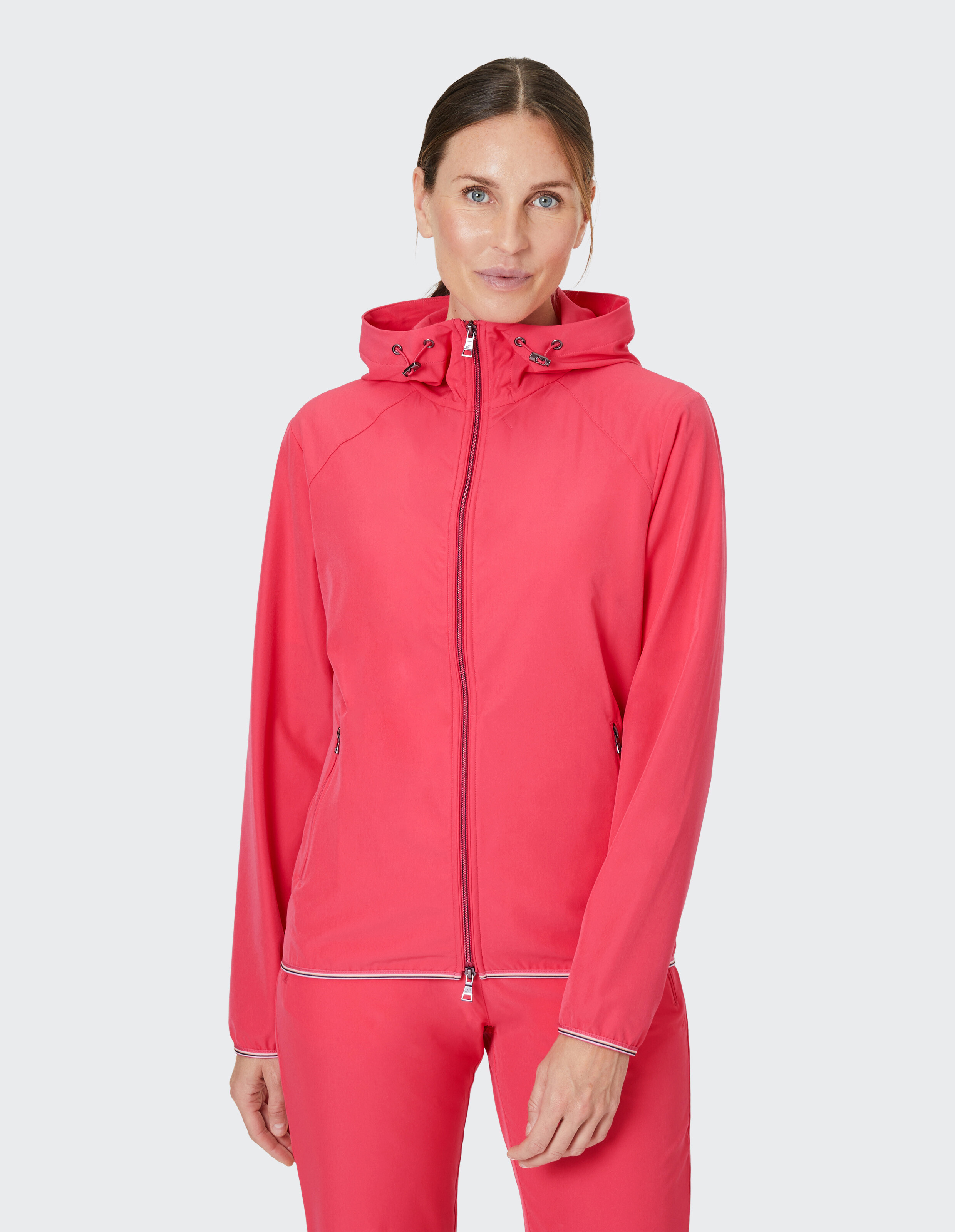 Leuchtend pinke Kapuzenjacke mit Reißverschluss, Kordelzug an der Kapuze und Taschen mit Reißverschlüssen, aus leichtem Stoff.