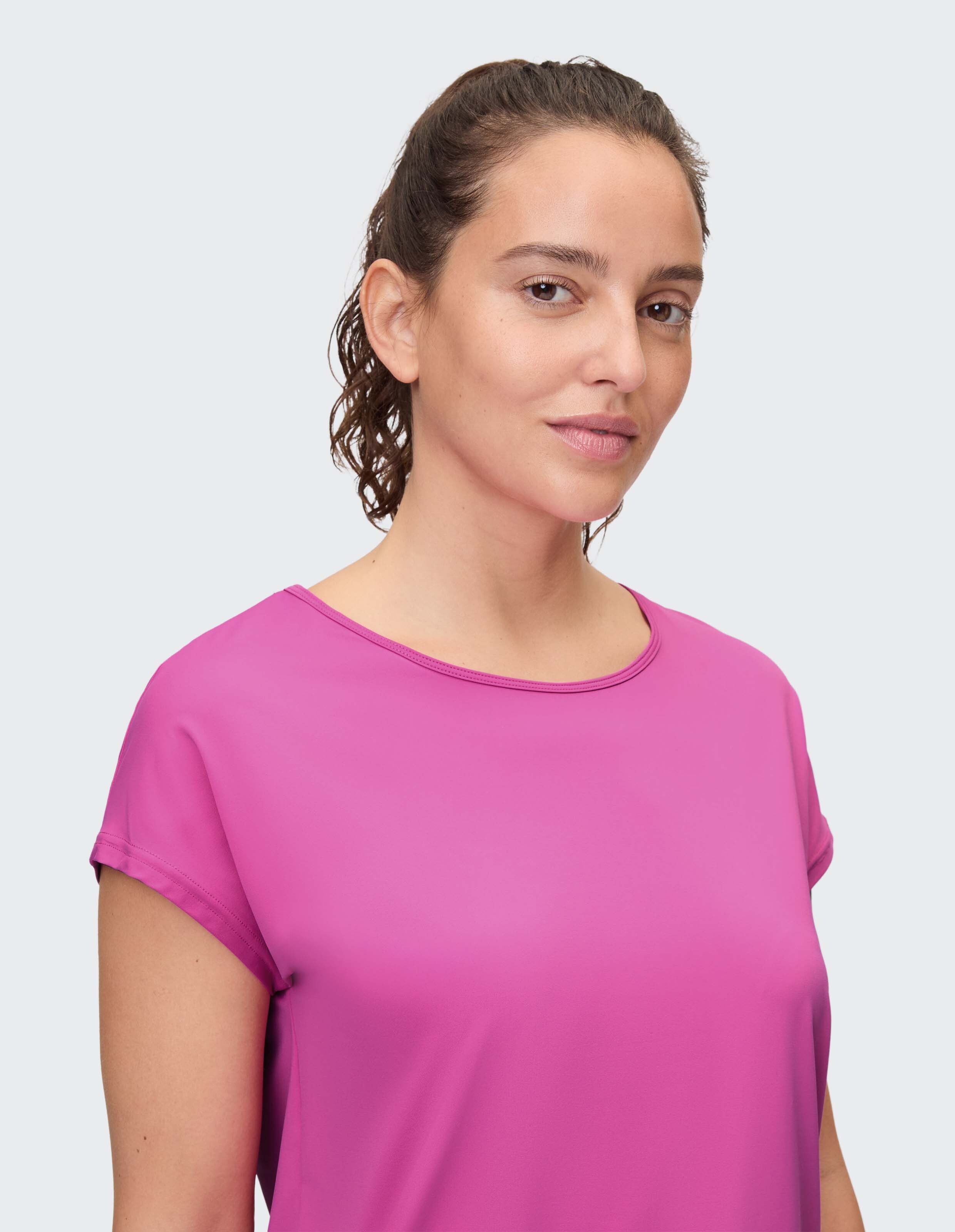 Frau trägt ein leuchtend rosa lässiges Kurzarmhemd für einen bequemen Alltagsstil.