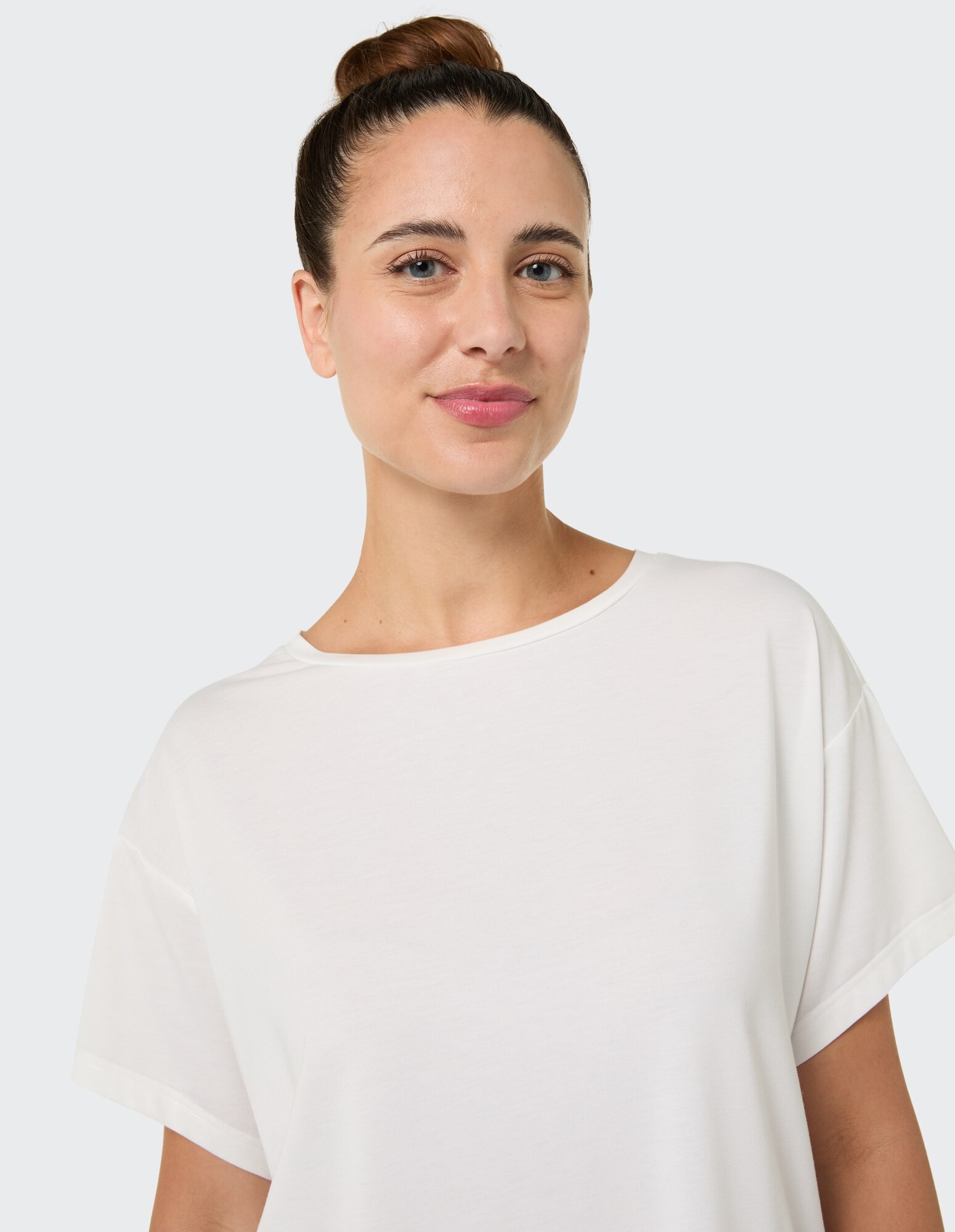 Nahaufnahme einer Frau in einem weißen Freizeit-T-Shirt, die einen entspannten Stil zeigt.