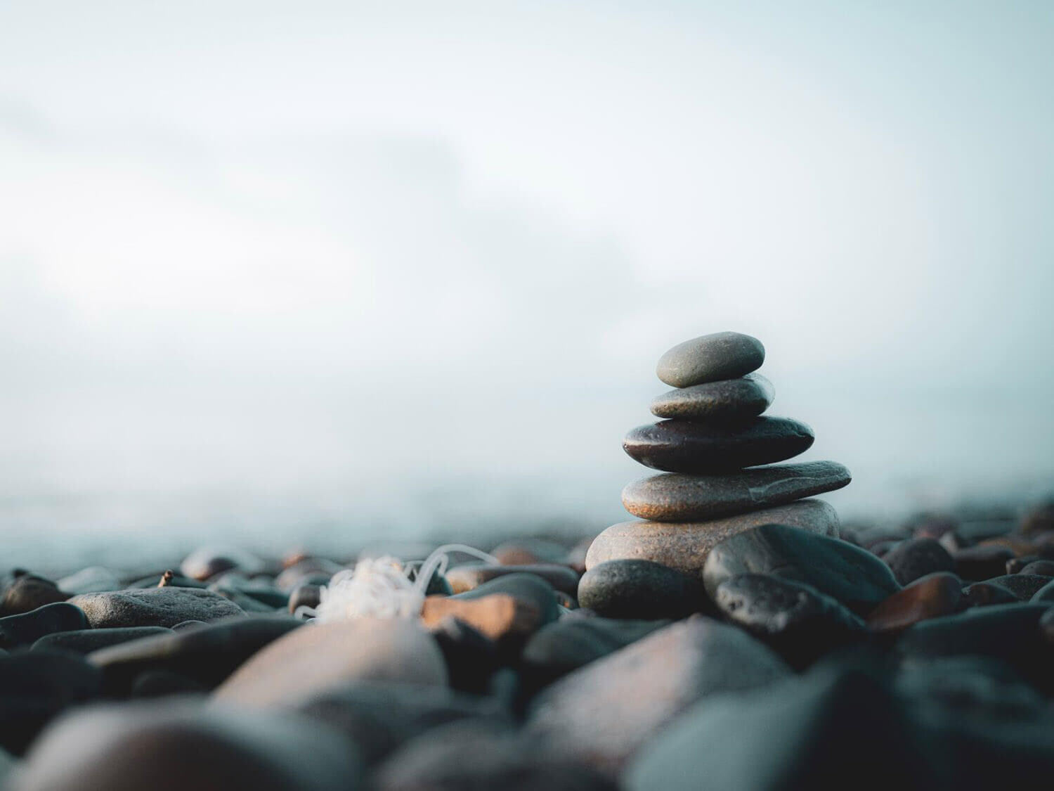 Stapel glatter Steine ​​an einem Kiesstrand mit weichem, verschwommenem Hintergrund.