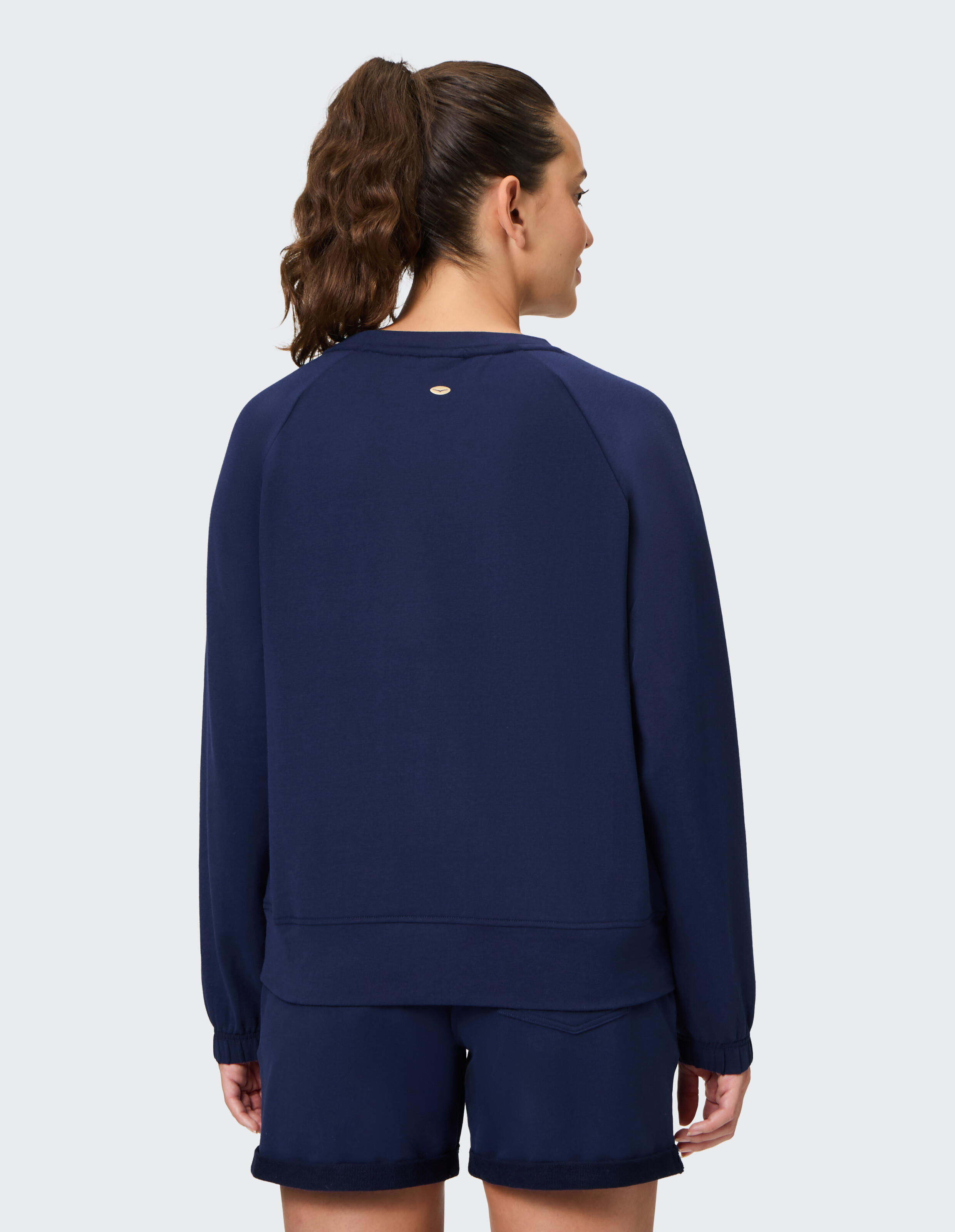 Frau trägt ein marineblaues, lässiges Sweatshirt mit langen Ärmeln und einem kleinen Logo-Detail.