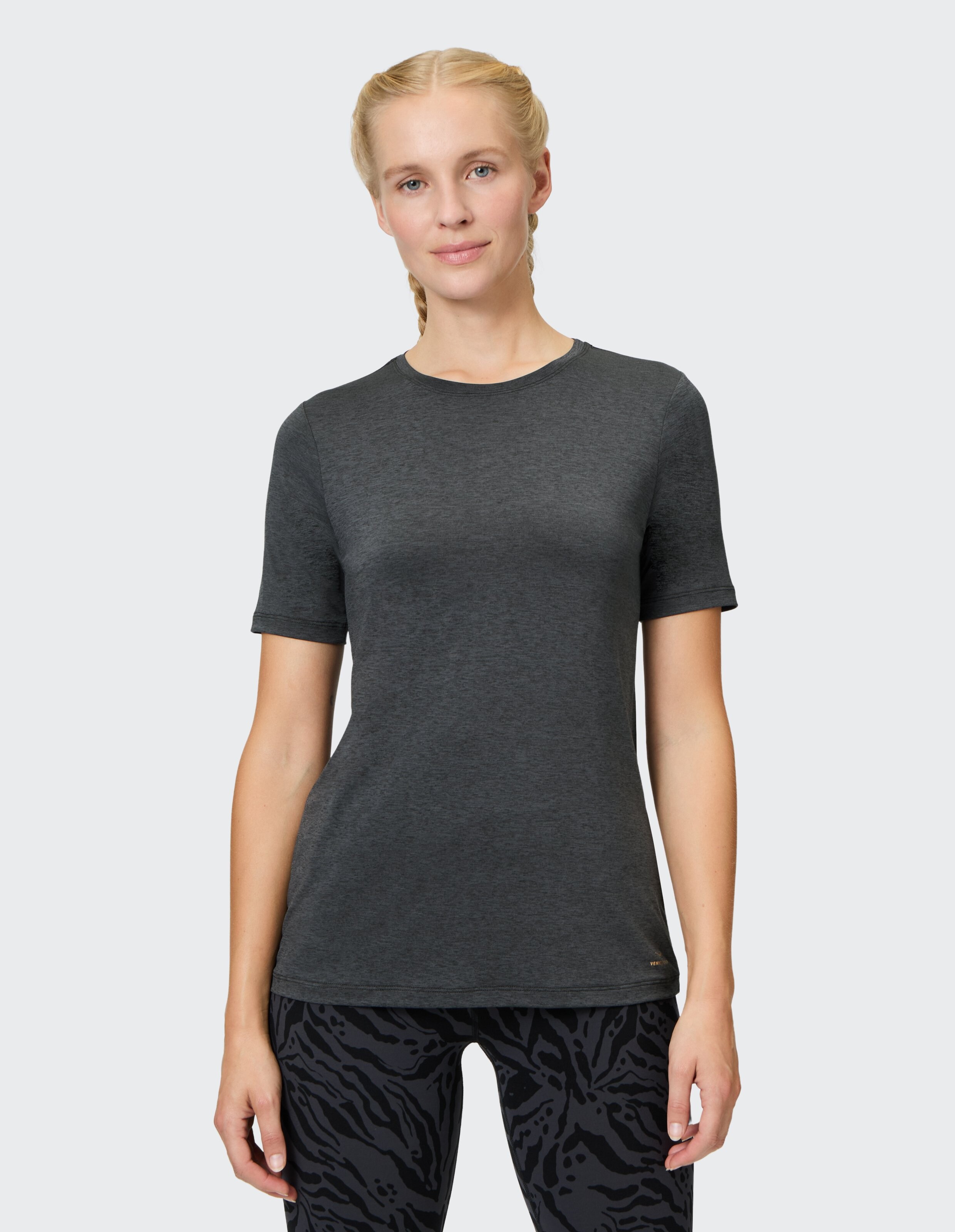 Frau in einem dunkelgrauen Kurzarm-T-Shirt gepaart mit gemusterten Leggings.