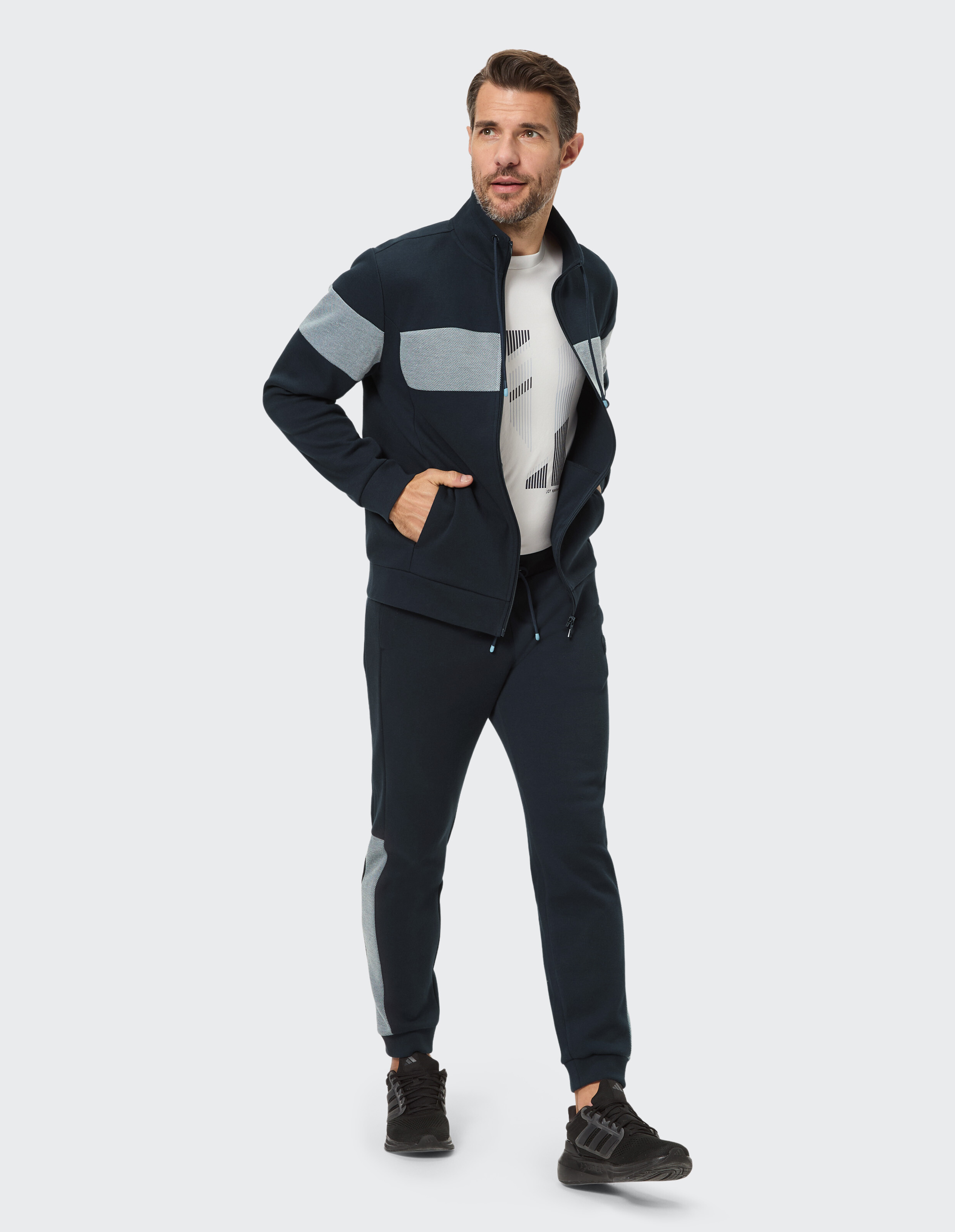 Mann im marineblauen Freizeit-Trainingsanzug mit grauen Akzenten, perfekt zum Faulenzen oder für Freizeitausflüge.