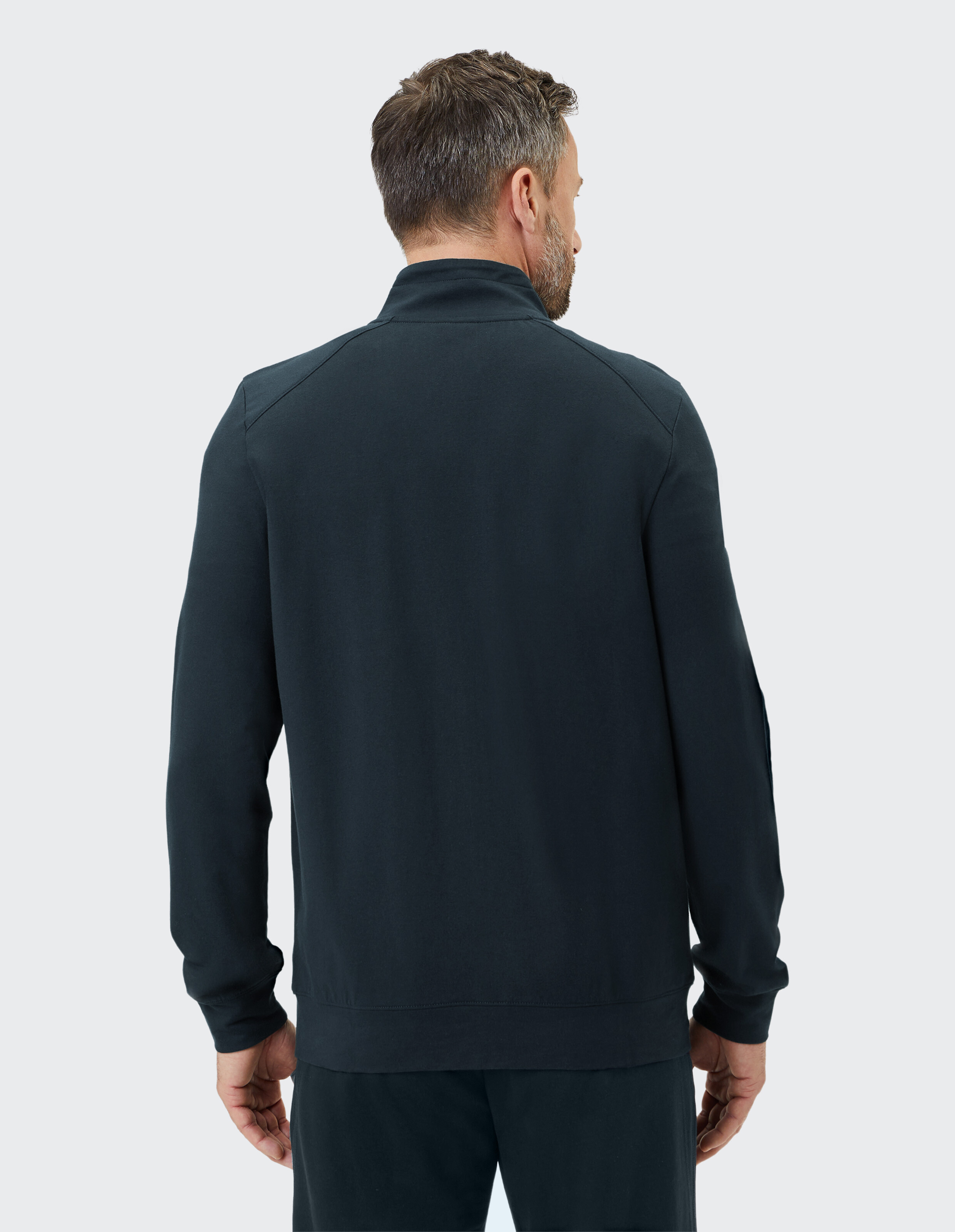 Mann trägt ein dunkelblaues, lässiges Sweatshirt mit Reißverschluss, Rückansicht, gemütlicher Loungewear-Stil.