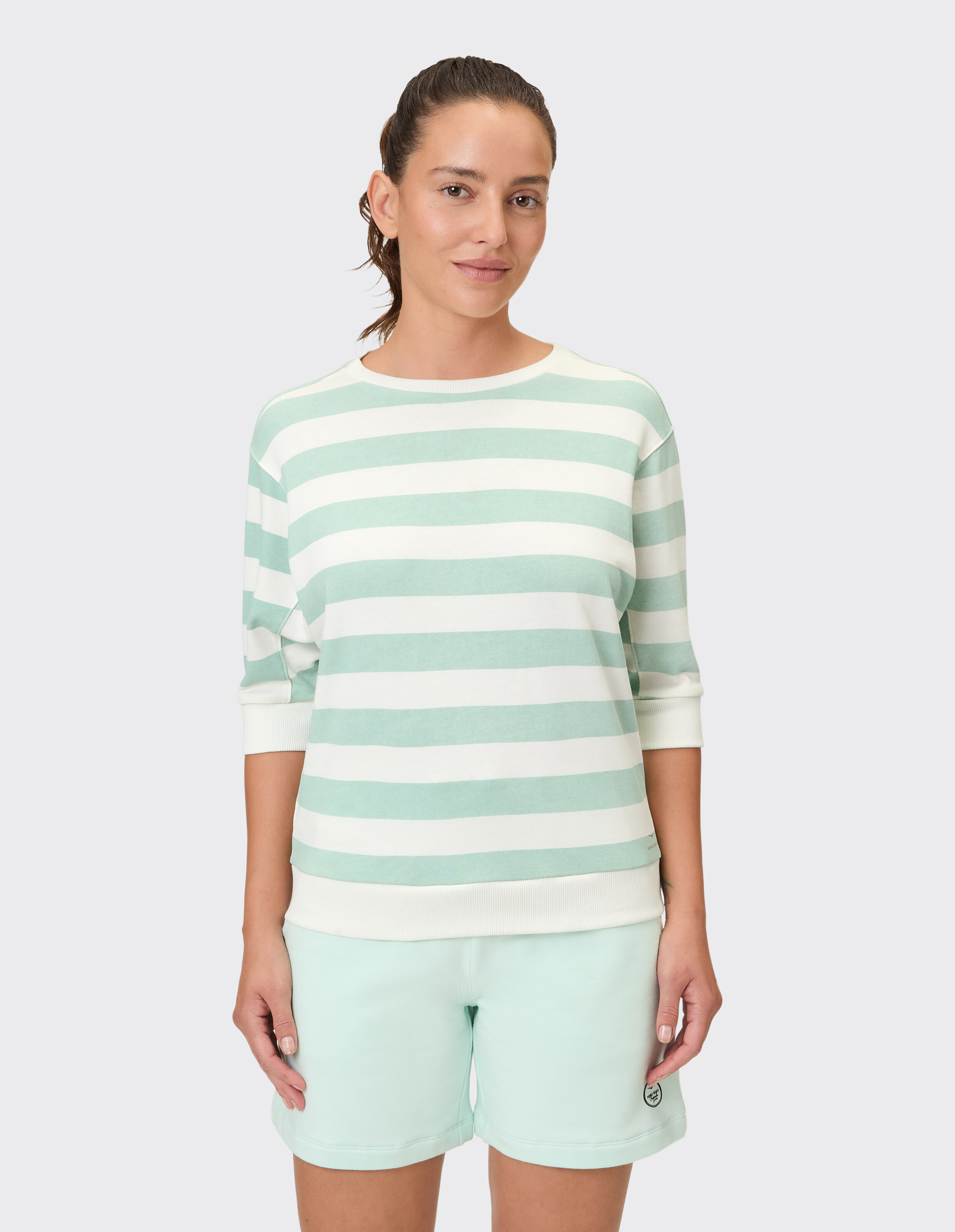 Frau trägt einen mintgrün gestreiften Pullover und passende Shorts im lässigen Stil.