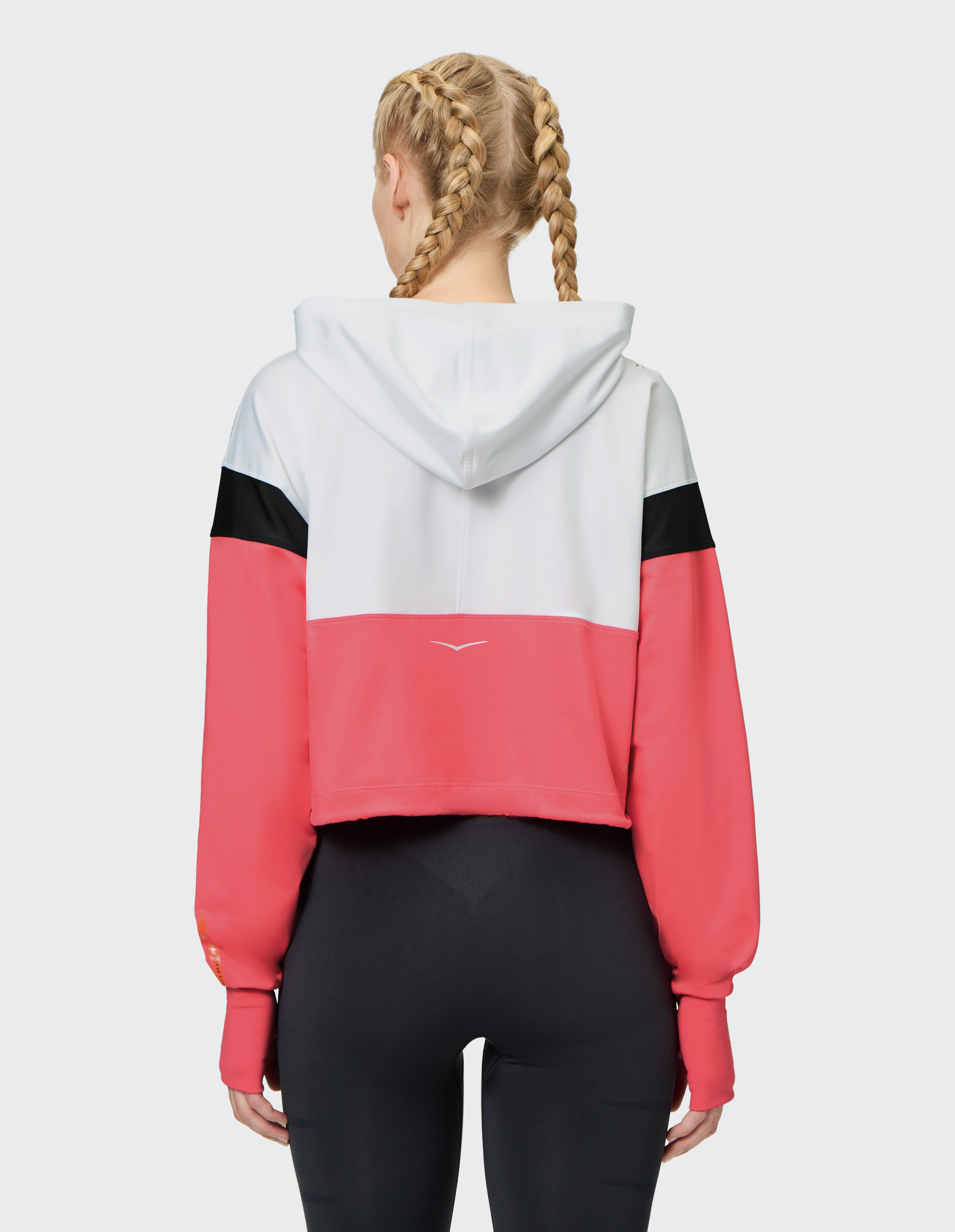 Rückansicht eines kurzen Kapuzenpullovers in Rosa, Weiß und Schwarz, perfekt für Freizeitkleidung.