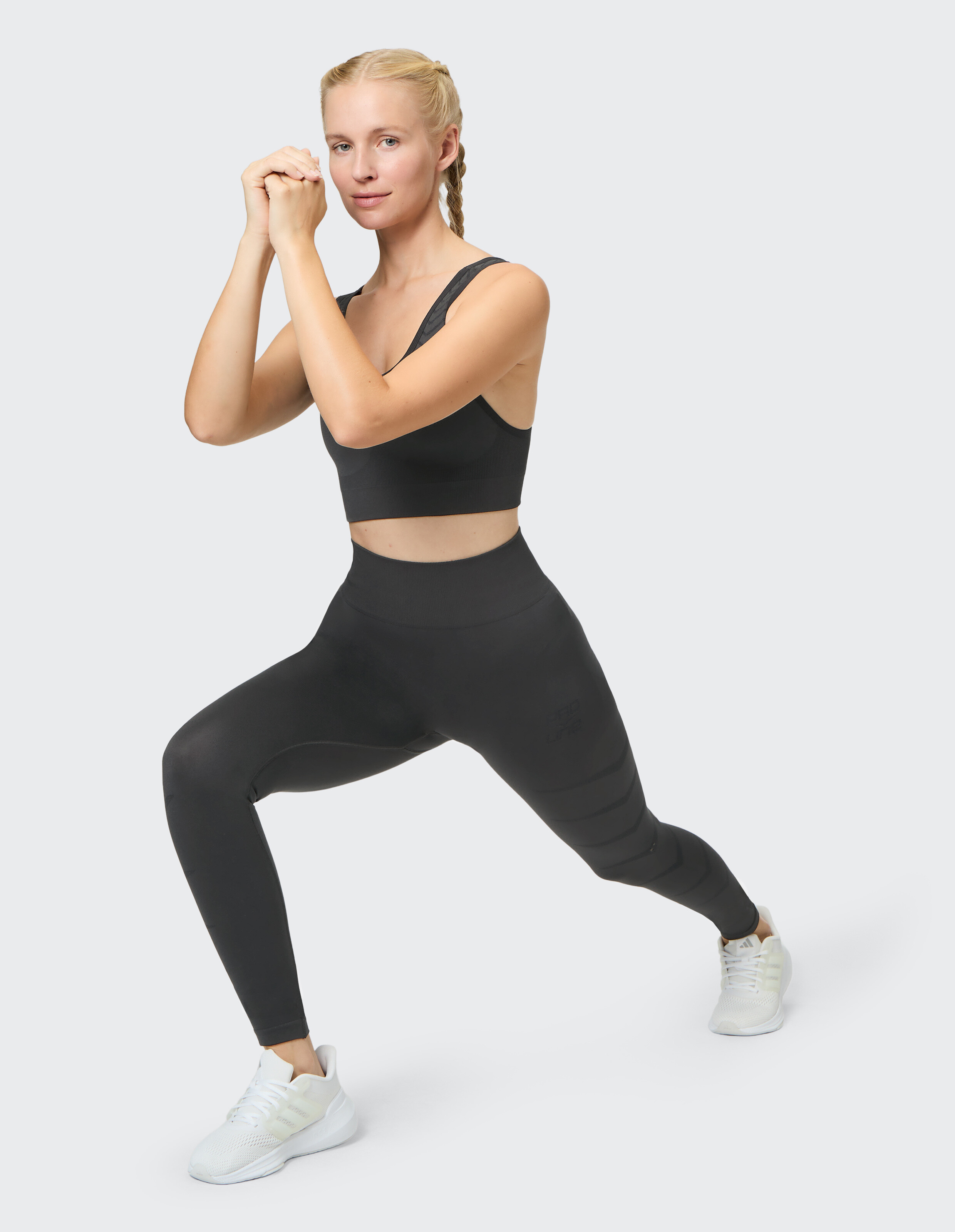 Model in schwarzem Sport-BH und Leggings, präsentiert Aktivkleidung für Fitness.
