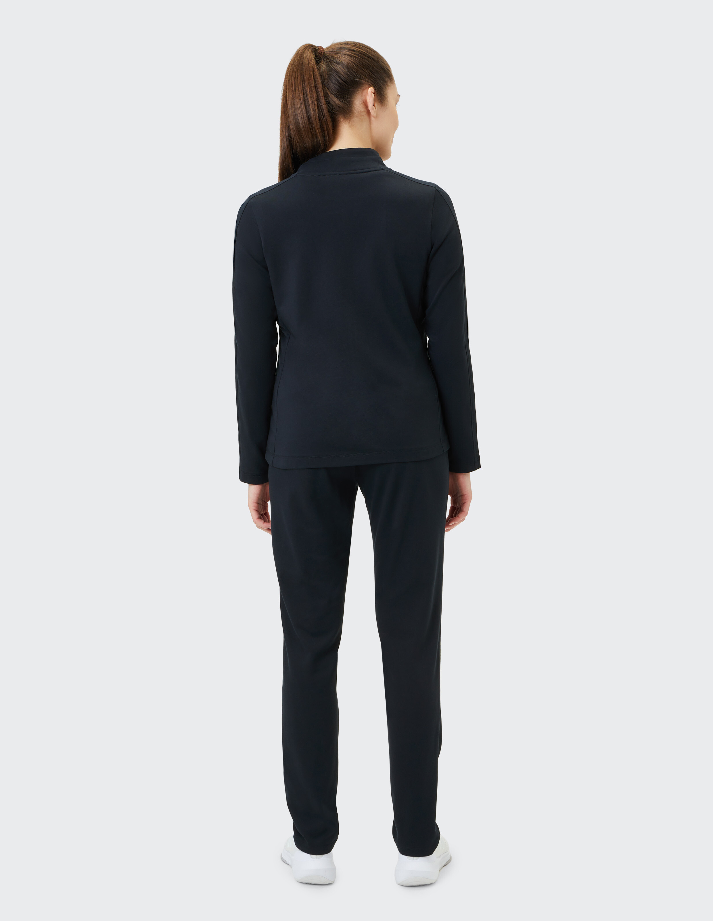 Frau trägt ein schwarzes Langarmshirt und eine passende Hose für einen gemütlichen, lässigen Look.